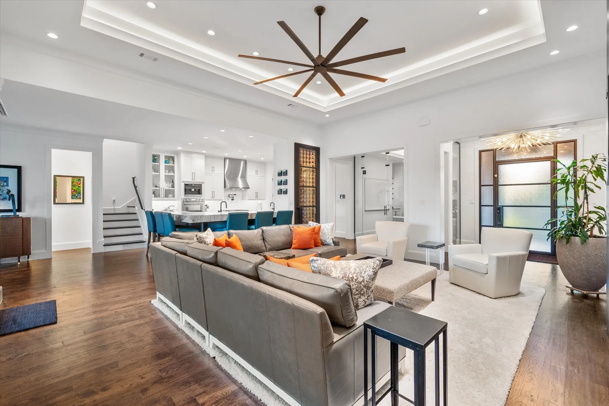 Open-concept living area featuring rich wood white oak finish flooring, a contemporary tray ceiling with recessed lighting, and a modern ceiling fan