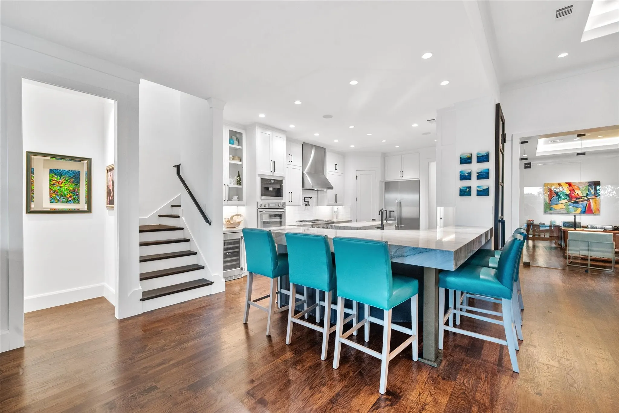 Open-concept kitchen featuring a large island with seating, stainless steel appliances, white cabinetry, and recessed lighting