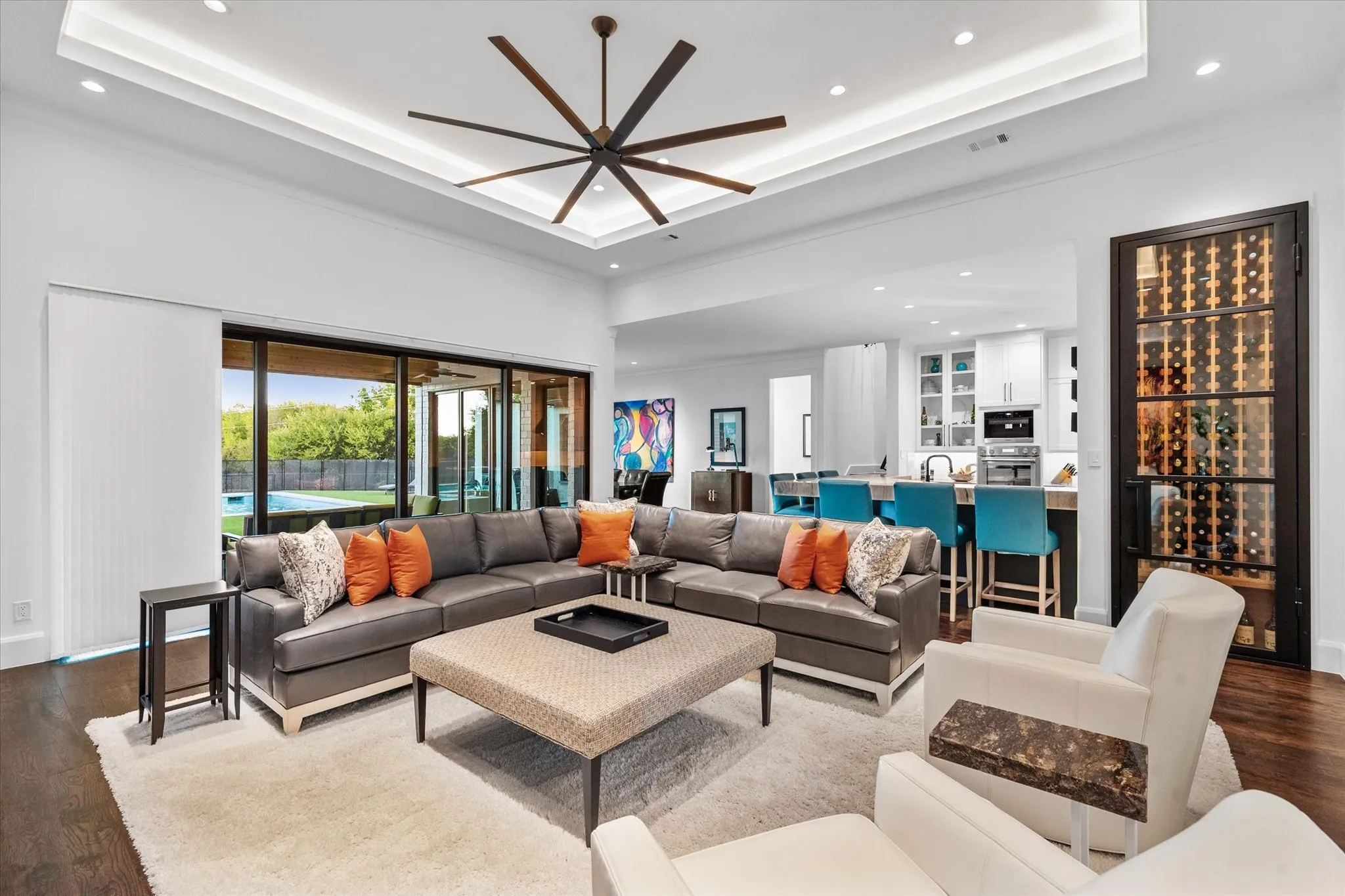 Open-concept living space featuring a tray ceiling with recessed lighting and a large ceiling fan