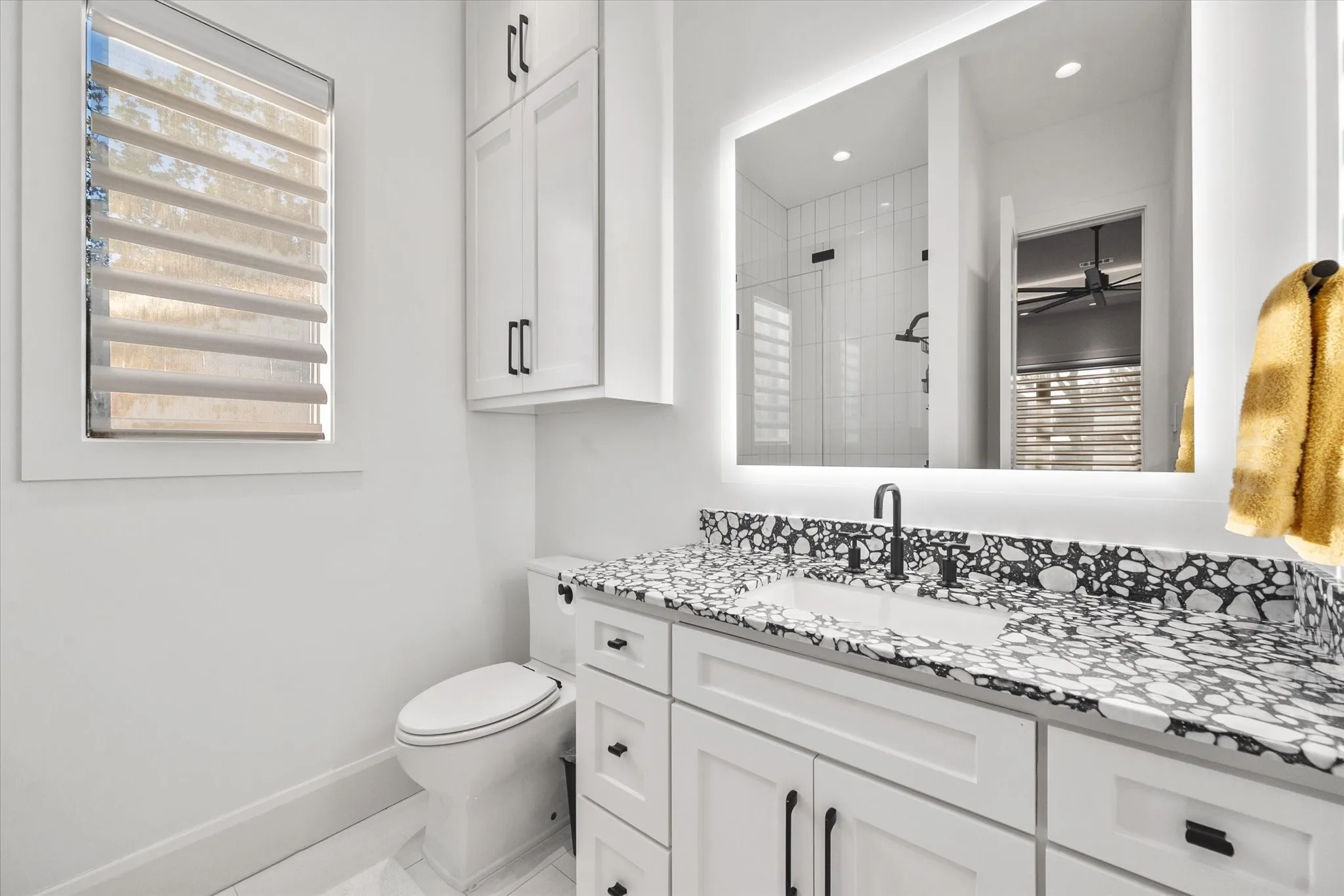 Contemporary vanity featuring a black and white patterned countertop, integrated sink, and matte black faucet