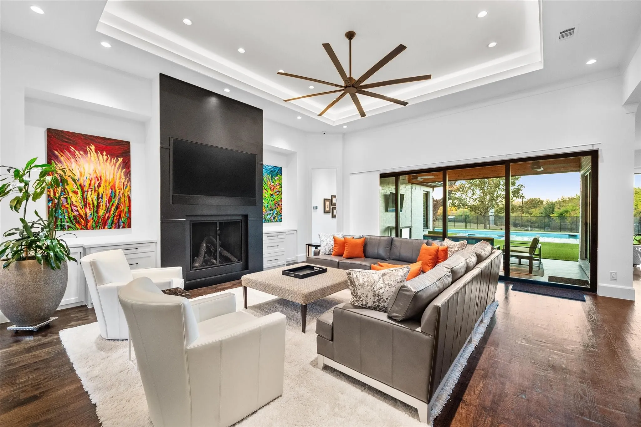 Living area featuring a modern linear fireplace, recessed lighting, and a tray ceiling with a large ceiling fan