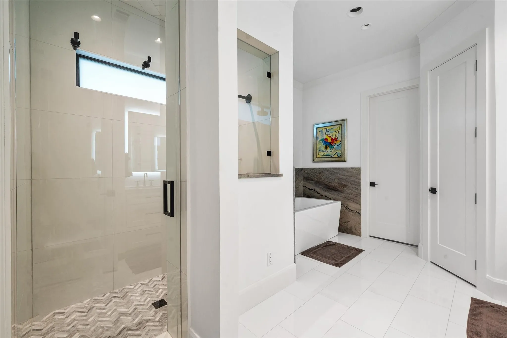 Glass-enclosed shower with a chevron-patterned tile floor and transom window