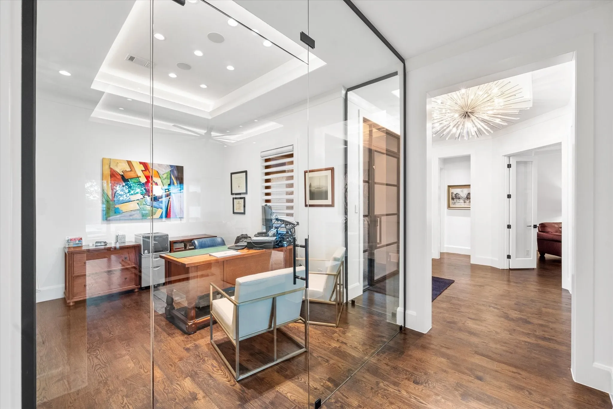 Private office space featuring full-height glass walls and dark wood-finish flooring