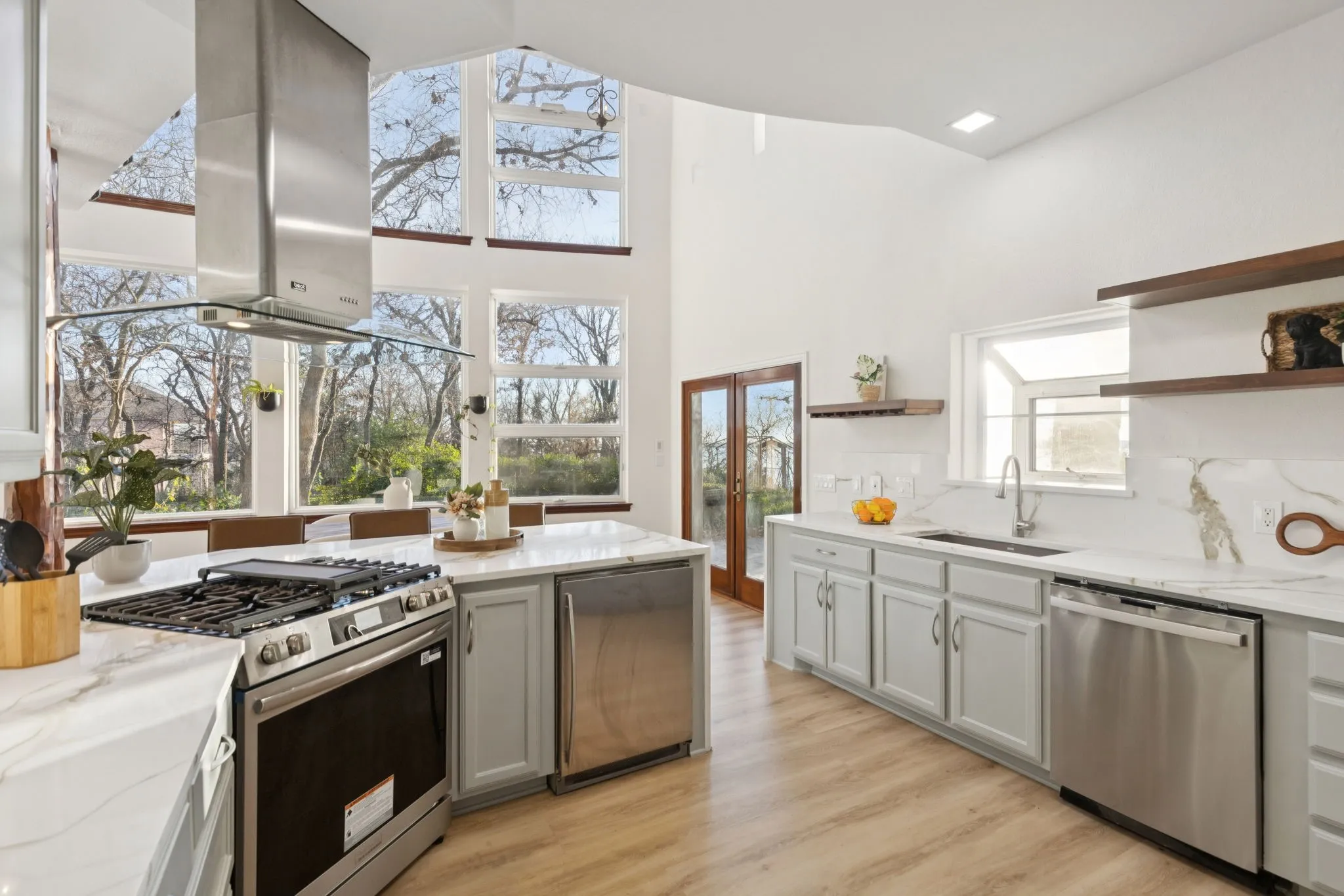 Kitchen featuring open shelves, appliances with stainless steel finishes, light stone counters, island exhaust hood, and lofted ceiling