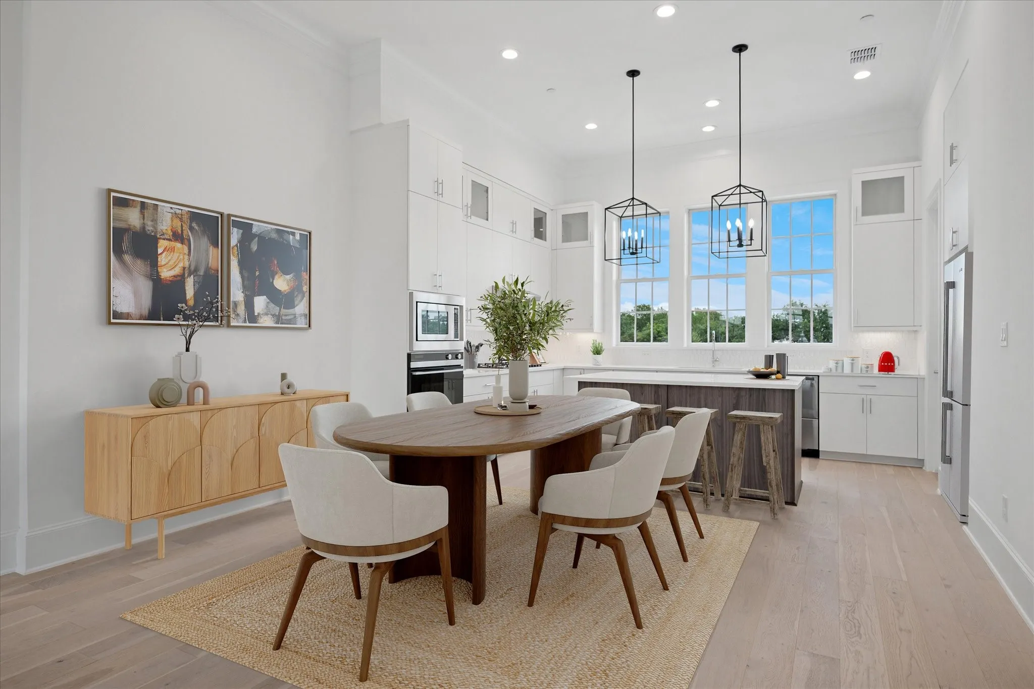 Open-concept kitchen and dining area featuring light wood-finish flooring, white cabinetry, and a large center island with seating