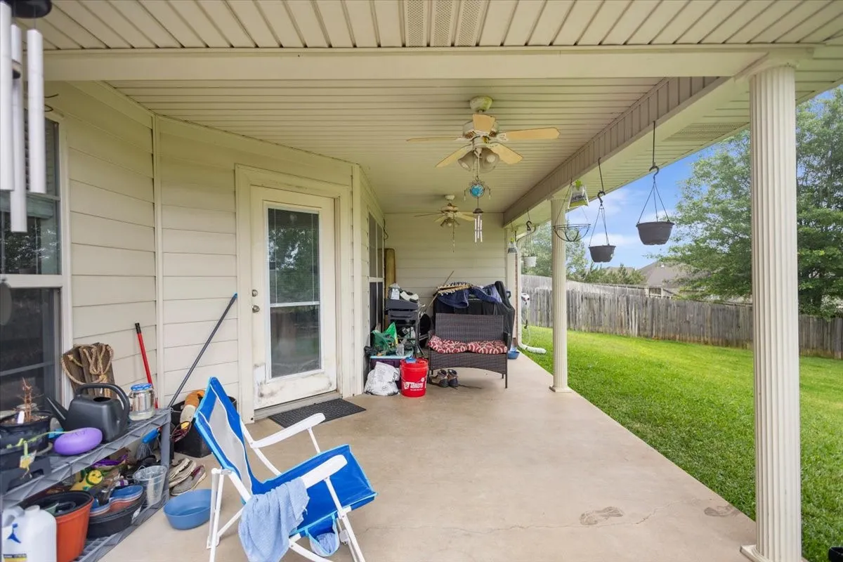 Expansive covered patio featuring a concrete surface, multiple ceiling fans, and a private rear yard with a wood fence