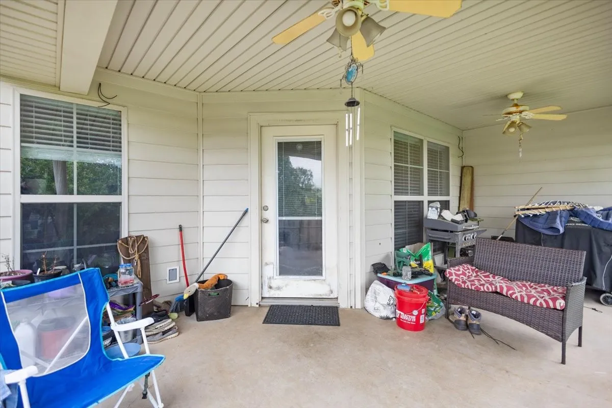 Spacious covered patio featuring a concrete surface, two ceiling fans, and a glass-paneled entry door