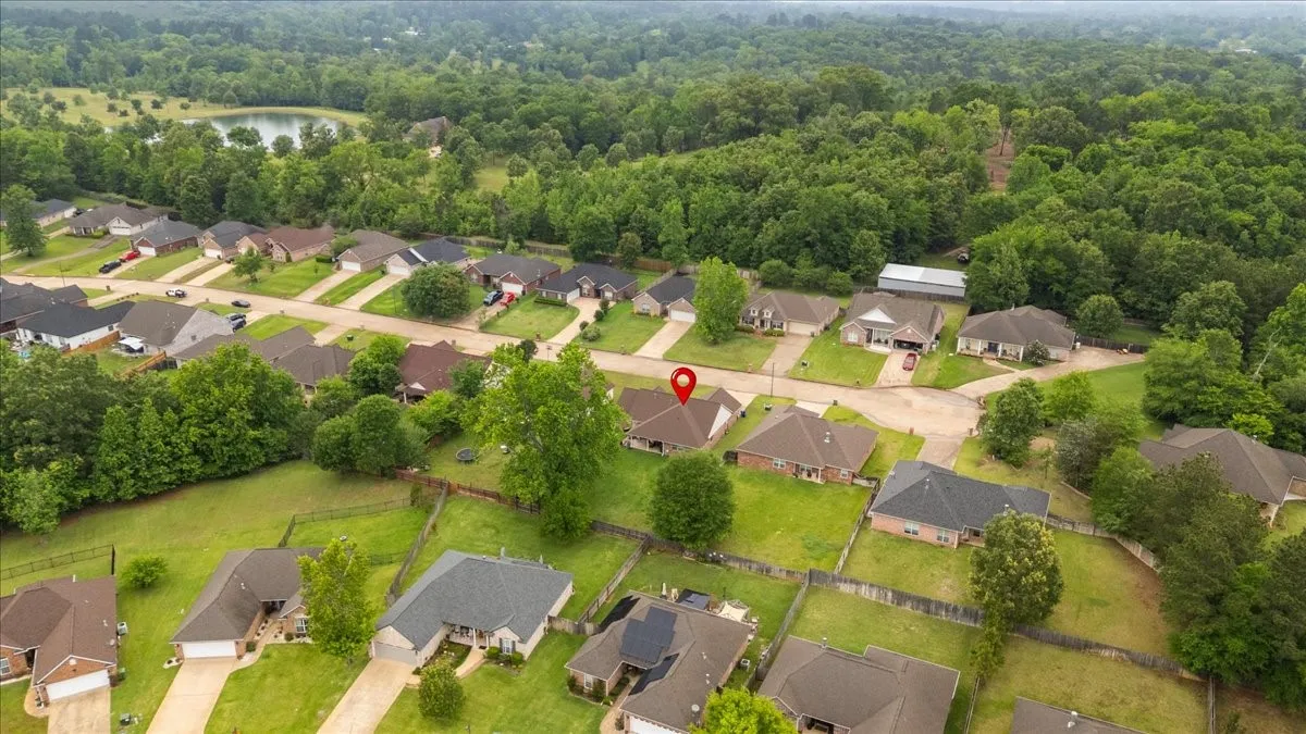 Residential neighborhood featuring single-story homes with pitched roofs, surrounded by mature trees and green spaces