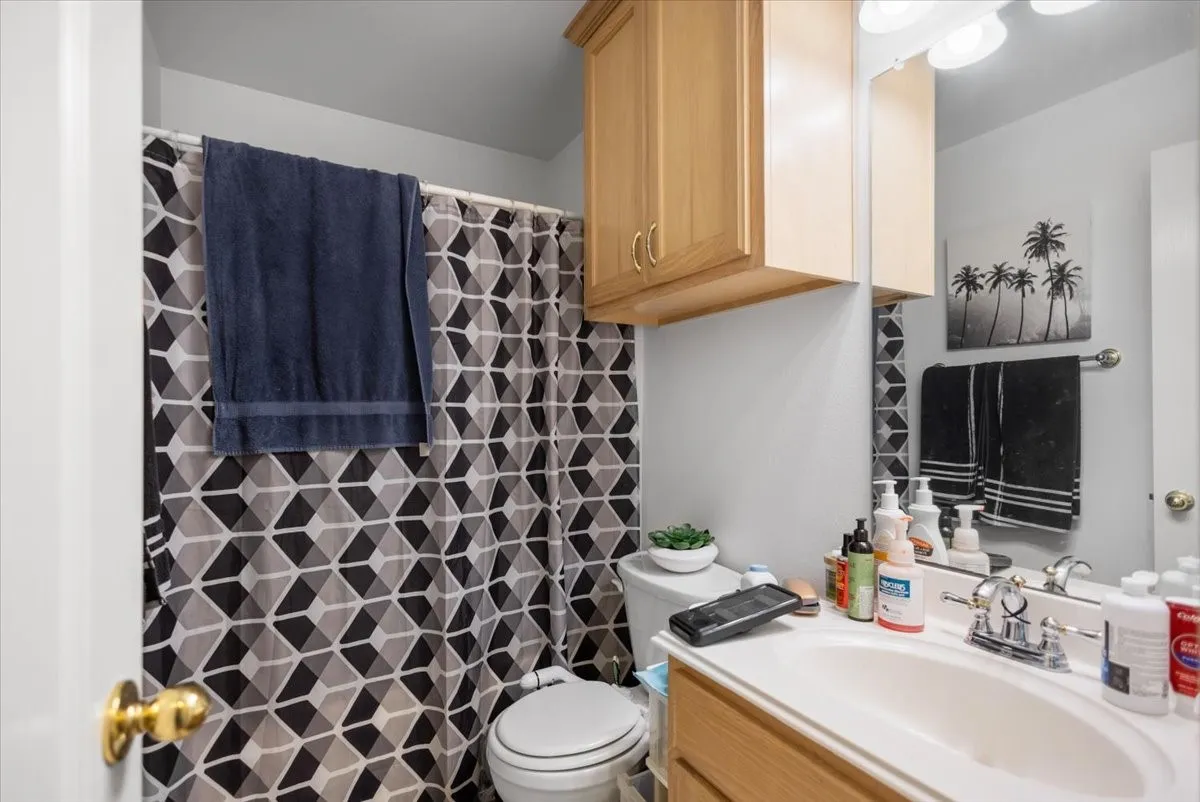 Bathroom featuring a wood-finish vanity with an integrated sink, polished chrome faucet, and a large wall-mounted mirror