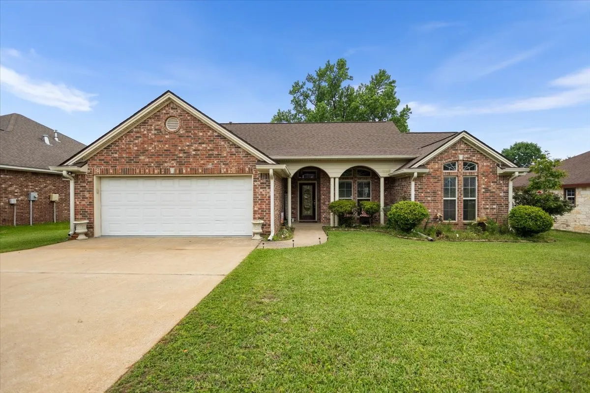 Brick exterior with a gabled roofline, arched portico, and an integrated two-car garage