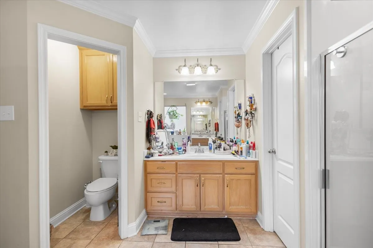 Bathroom featuring a wood-finish vanity with an integrated sink, a framed mirror, and a three-light fixture
