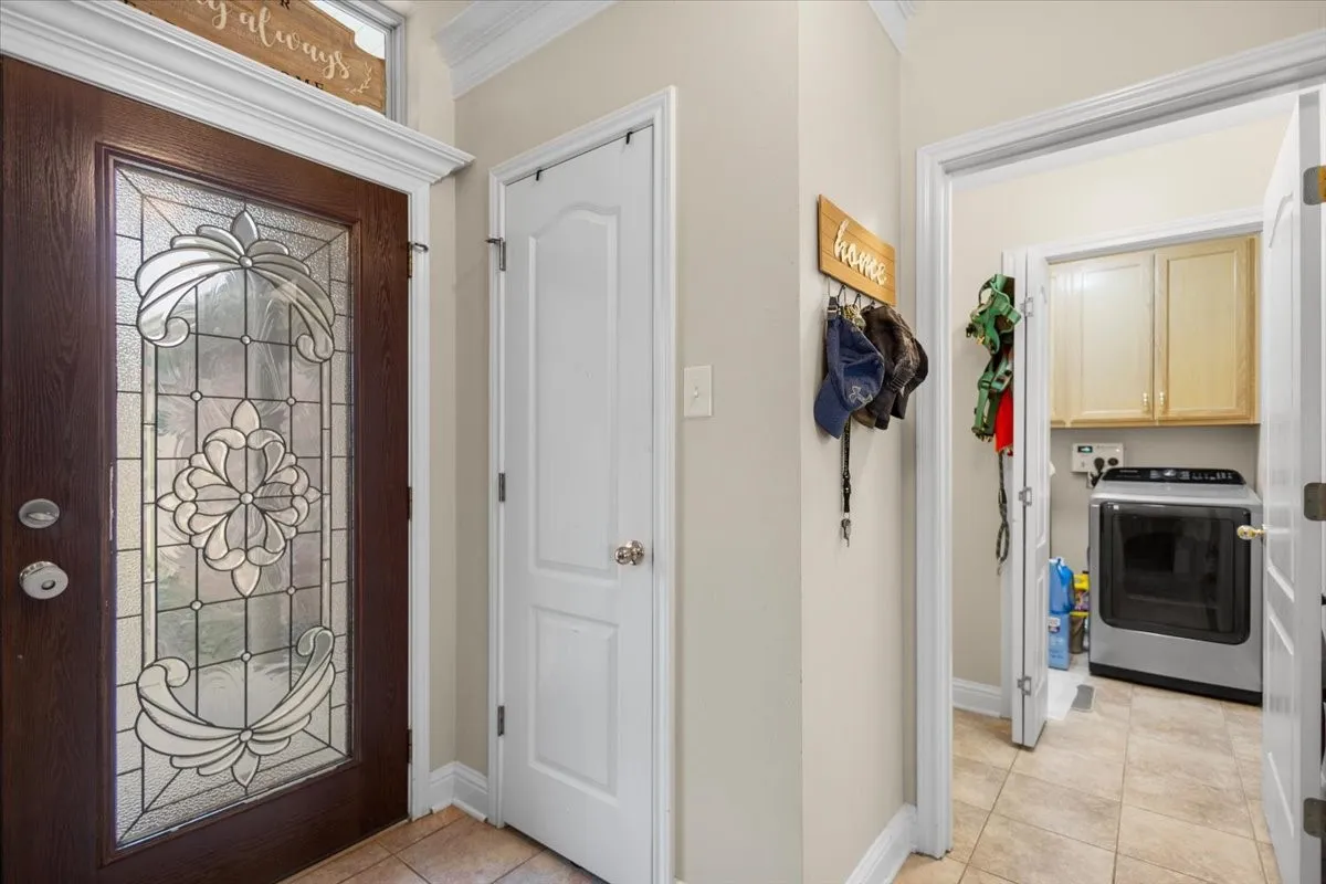 Entryway featuring a decorative glass-paneled wood-finish door, light-colored wall paint, white trim, and tiled flooring