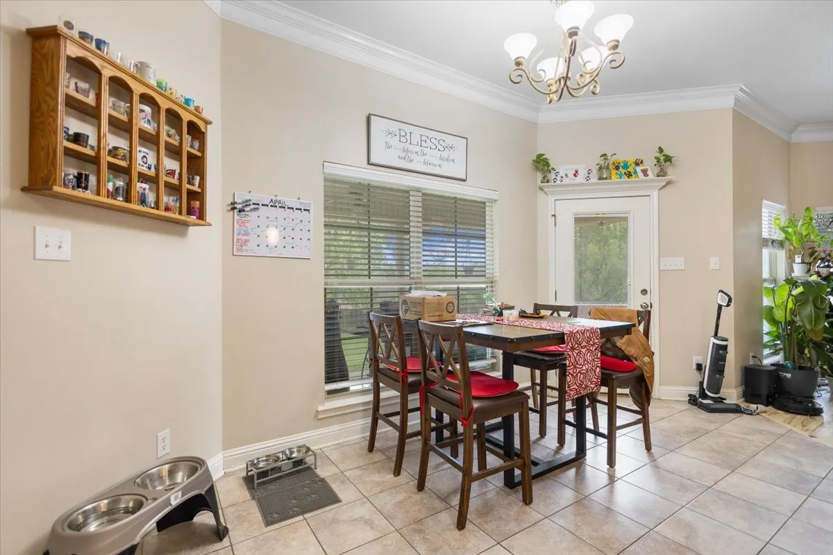 Dining area featuring crown molding, a window with blinds, and tile flooring