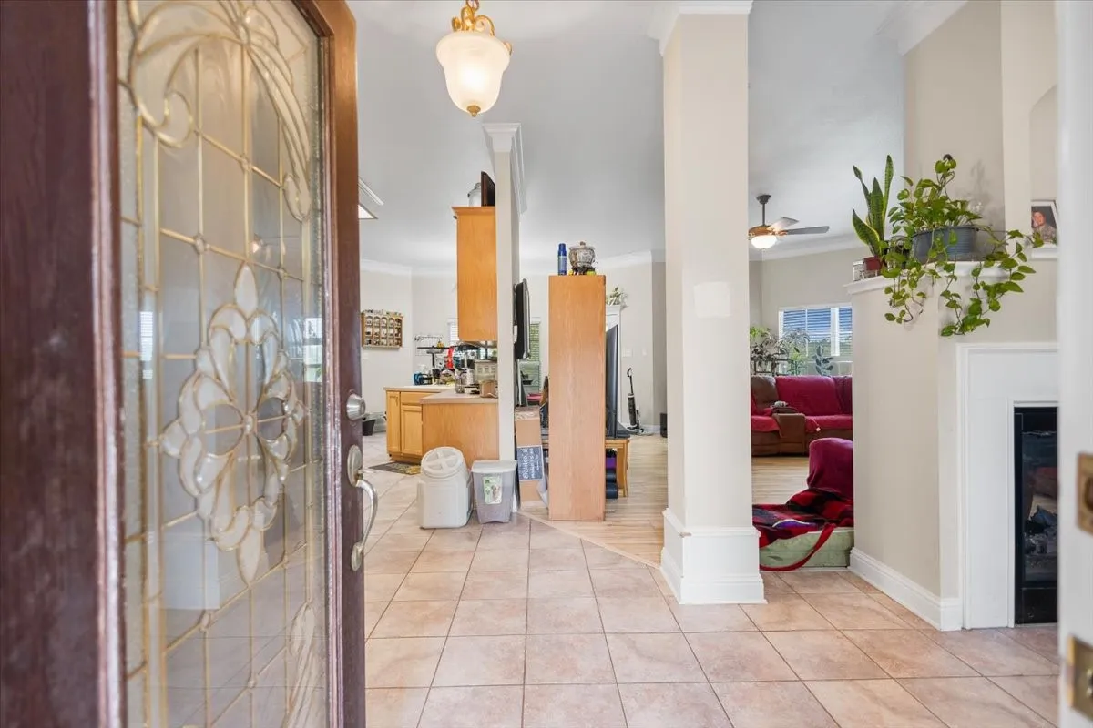 Entryway featuring a decorative leaded glass door, neutral tile flooring, crown molding, and a built-in fireplace