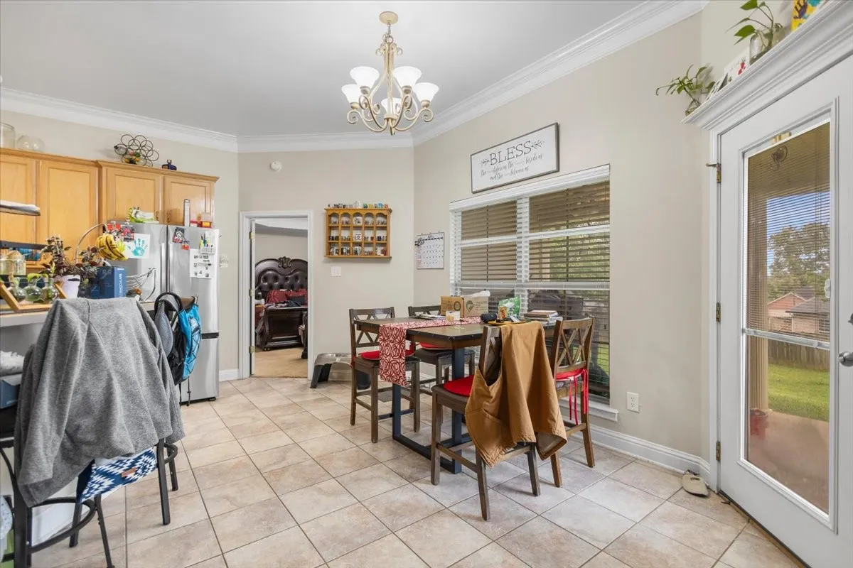 Kitchen and dining area featuring tile flooring, light wood cabinetry, and a window with blinds
