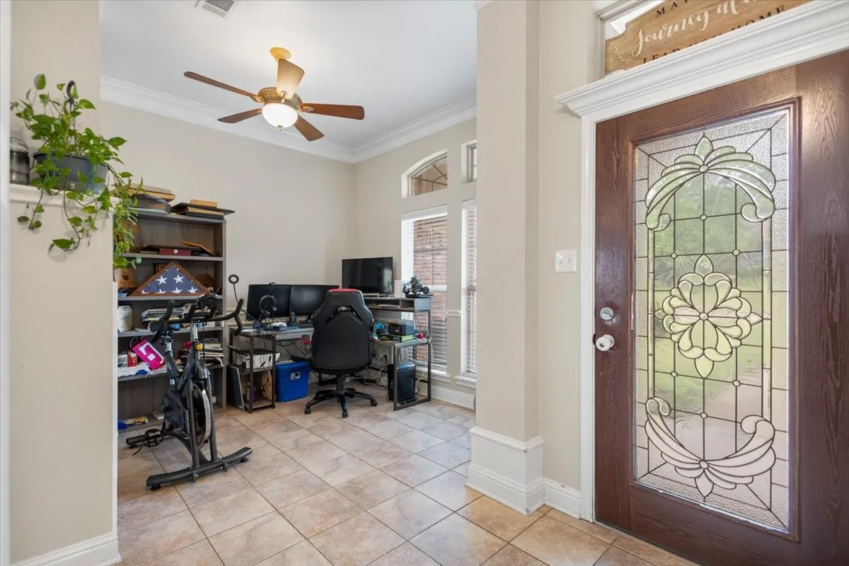 Entryway featuring a wood-finish door with decorative glass, crown molding, and a ceiling fan