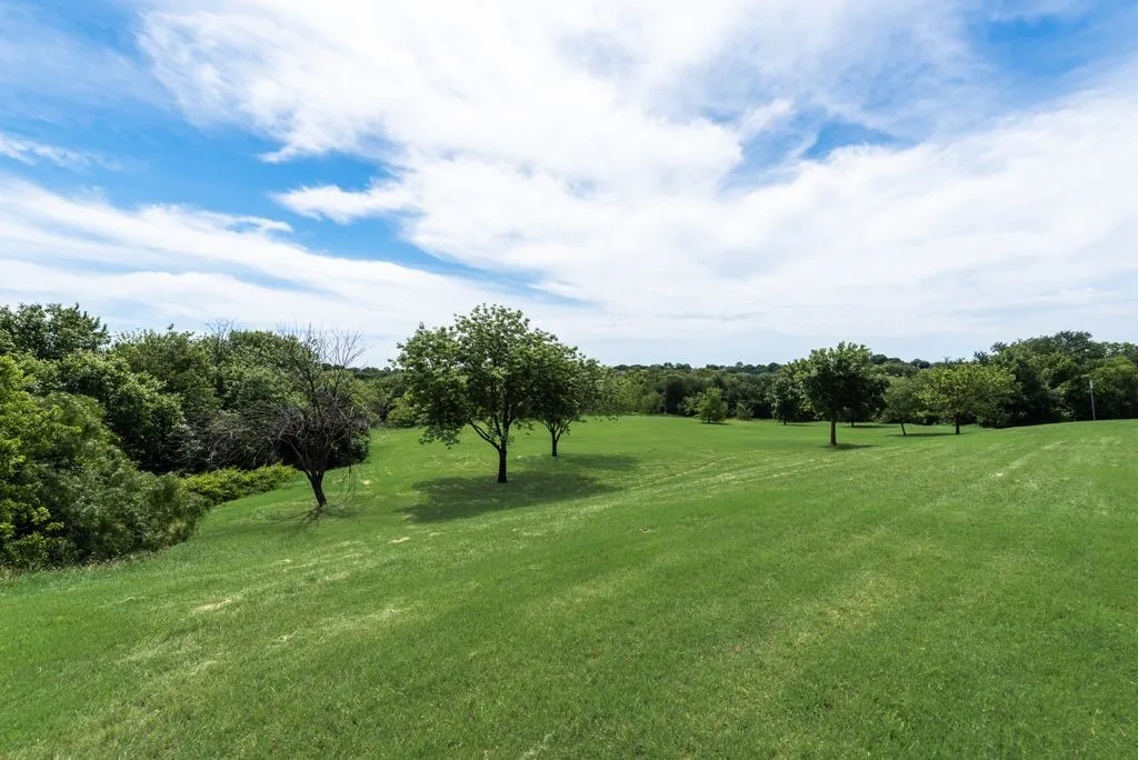 Expansive green lawn surrounded by mature trees, offering a significant outdoor space