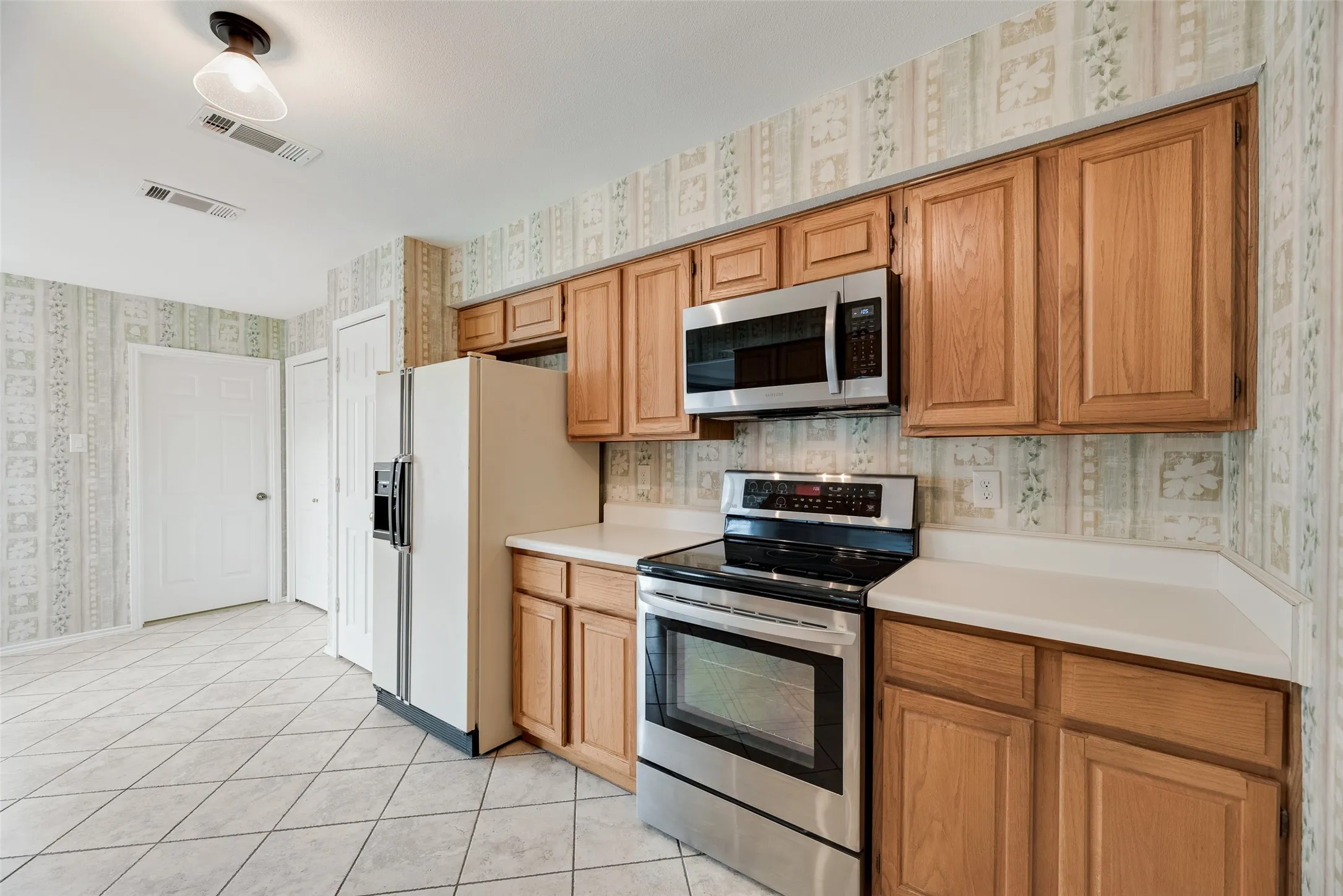 Kitchen featuring wood cabinetry, white countertops, a stainless steel range, and a stainless steel microwave