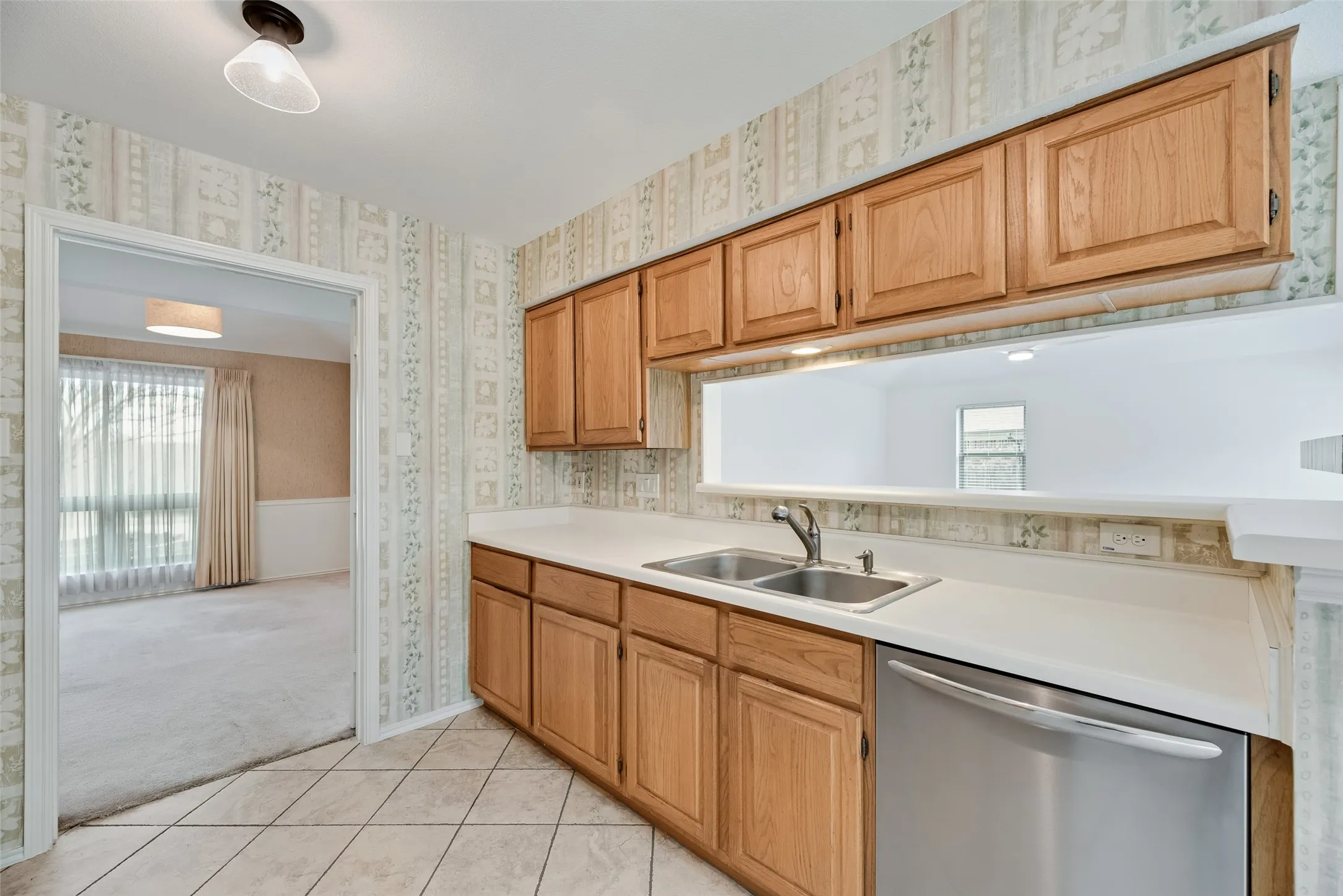Kitchen featuring wood cabinetry, a double basin stainless steel sink, and a stainless steel dishwasher