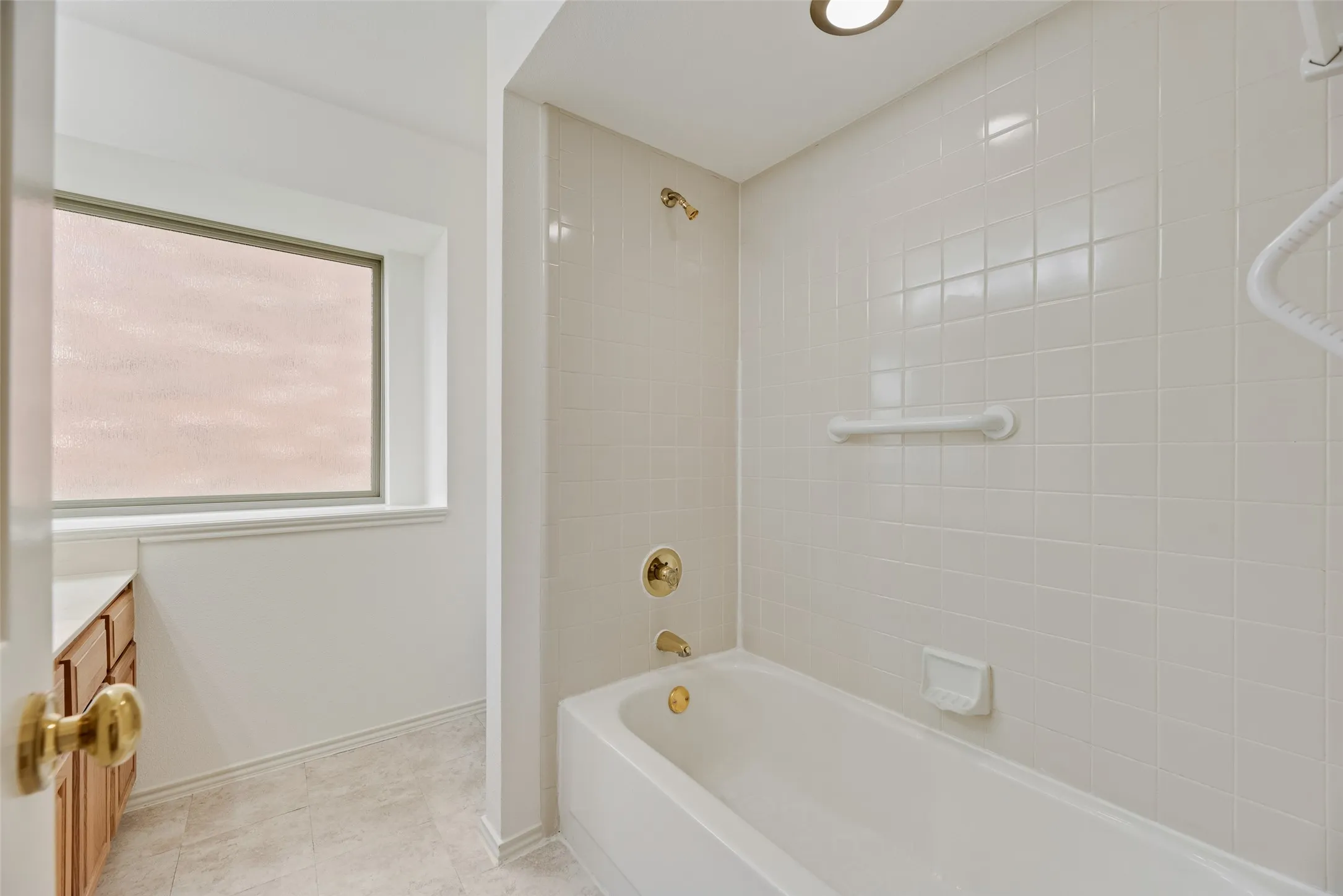 Bathroom featuring a white subway tile surround bathtub with brass fixtures