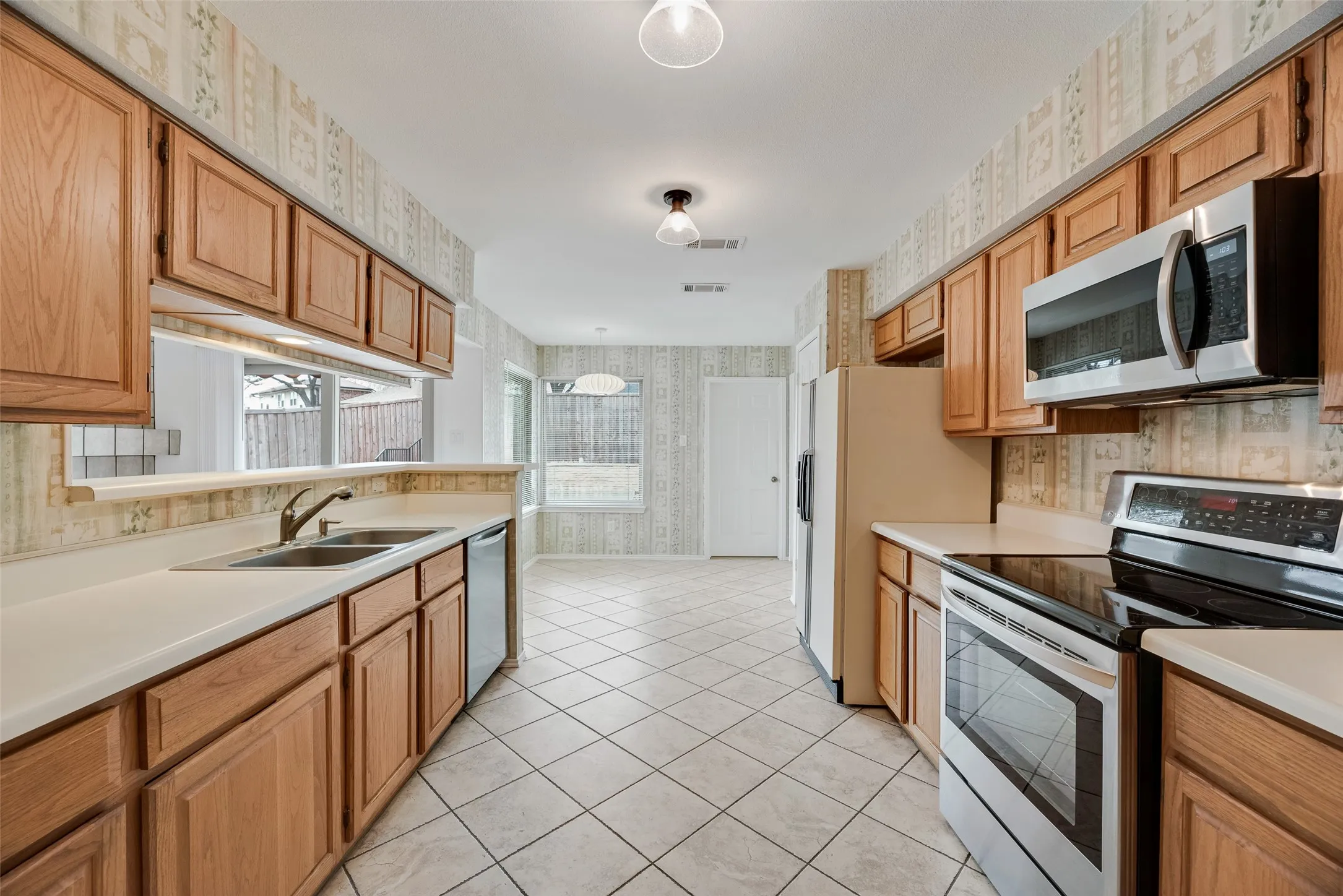 Kitchen featuring wood cabinetry, white countertops, a stainless steel sink, and a stainless steel oven with an overhead microwave