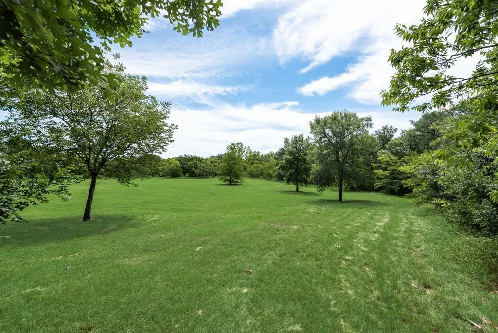 Spacious green lawn surrounded by mature trees, creating a private outdoor setting