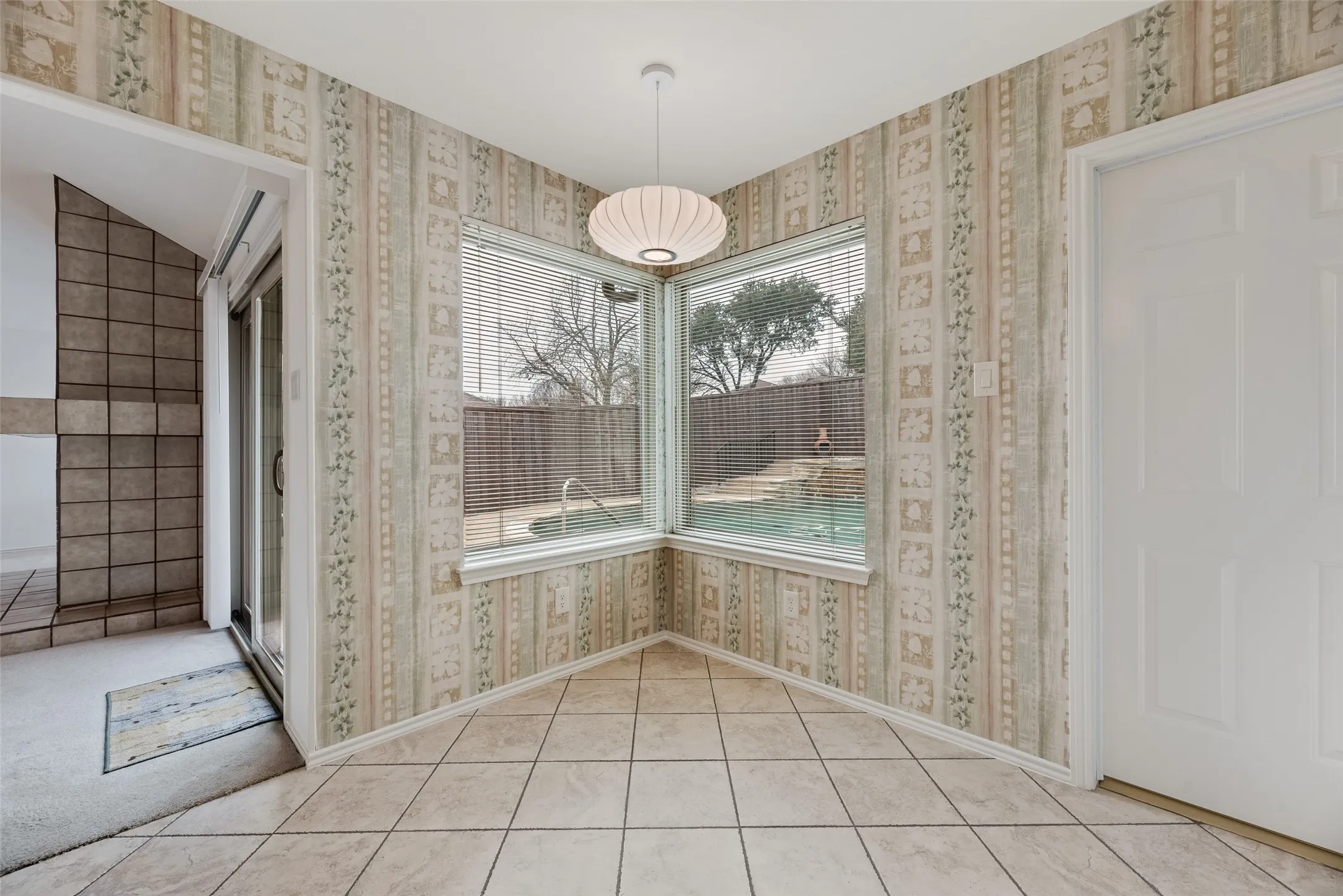 Corner windows with a pool view, tiled flooring, pendant lighting, and direct outdoor access