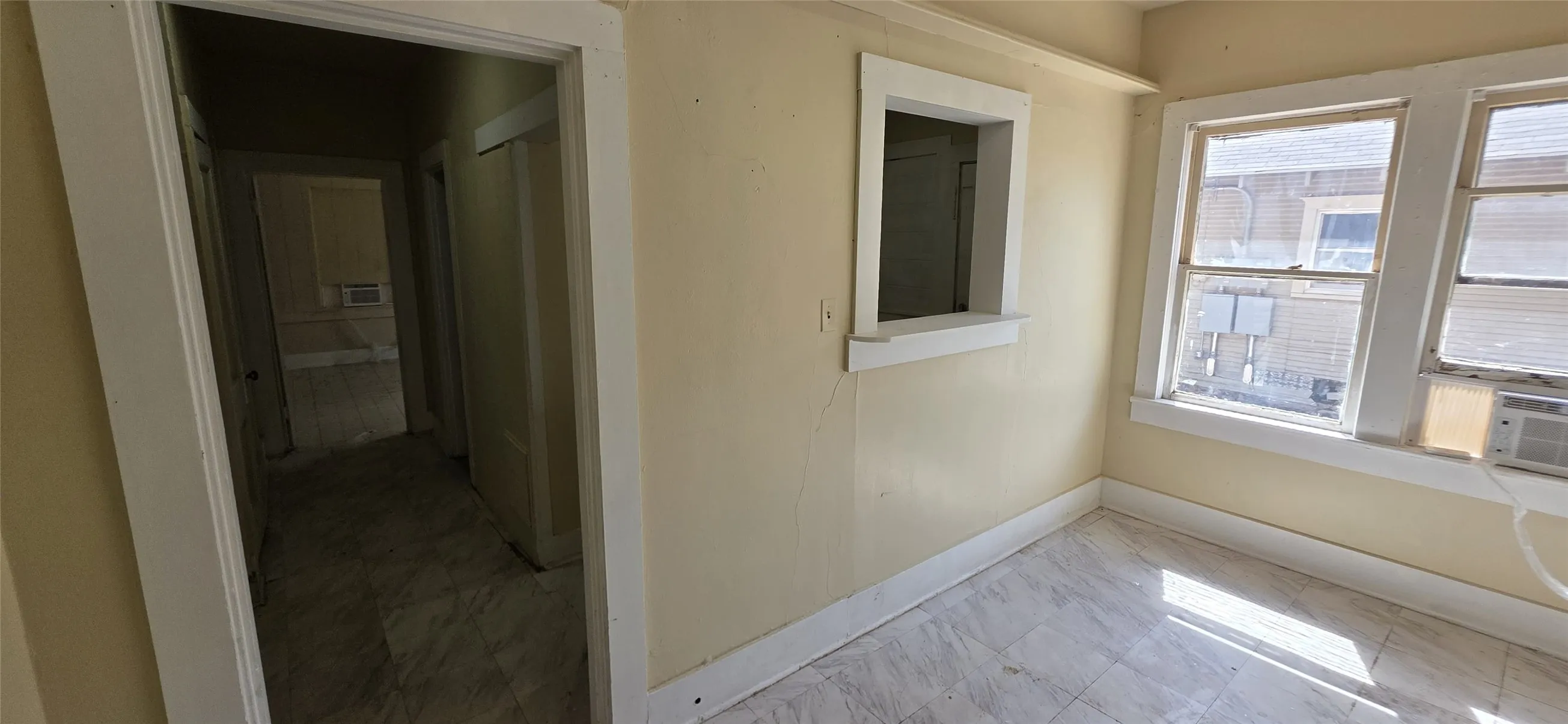 Room featuring two double-hung windows, a pass-through window opening, and light-toned flooring