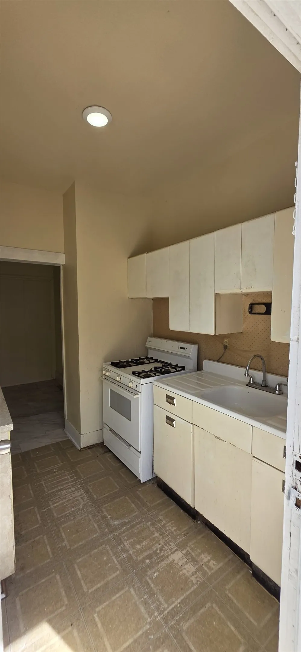 Kitchen featuring white upper cabinetry, white gas range, and a single-basin sink with a two-handle faucet