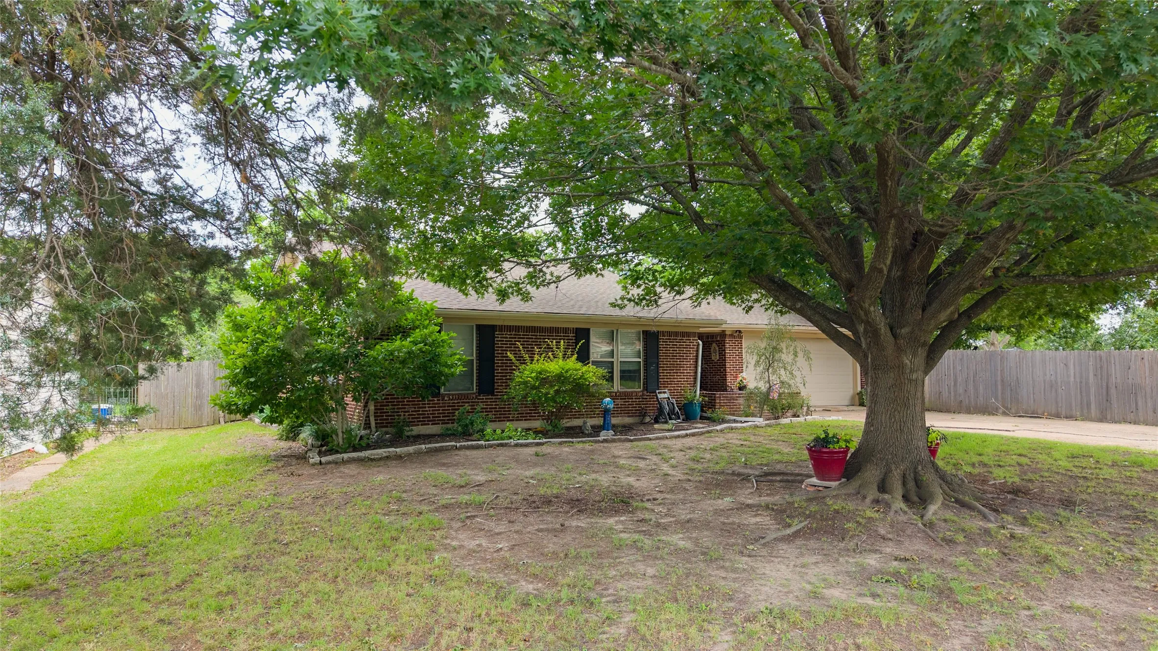 Ranch-style home with a brick facade and a prominent mature tree