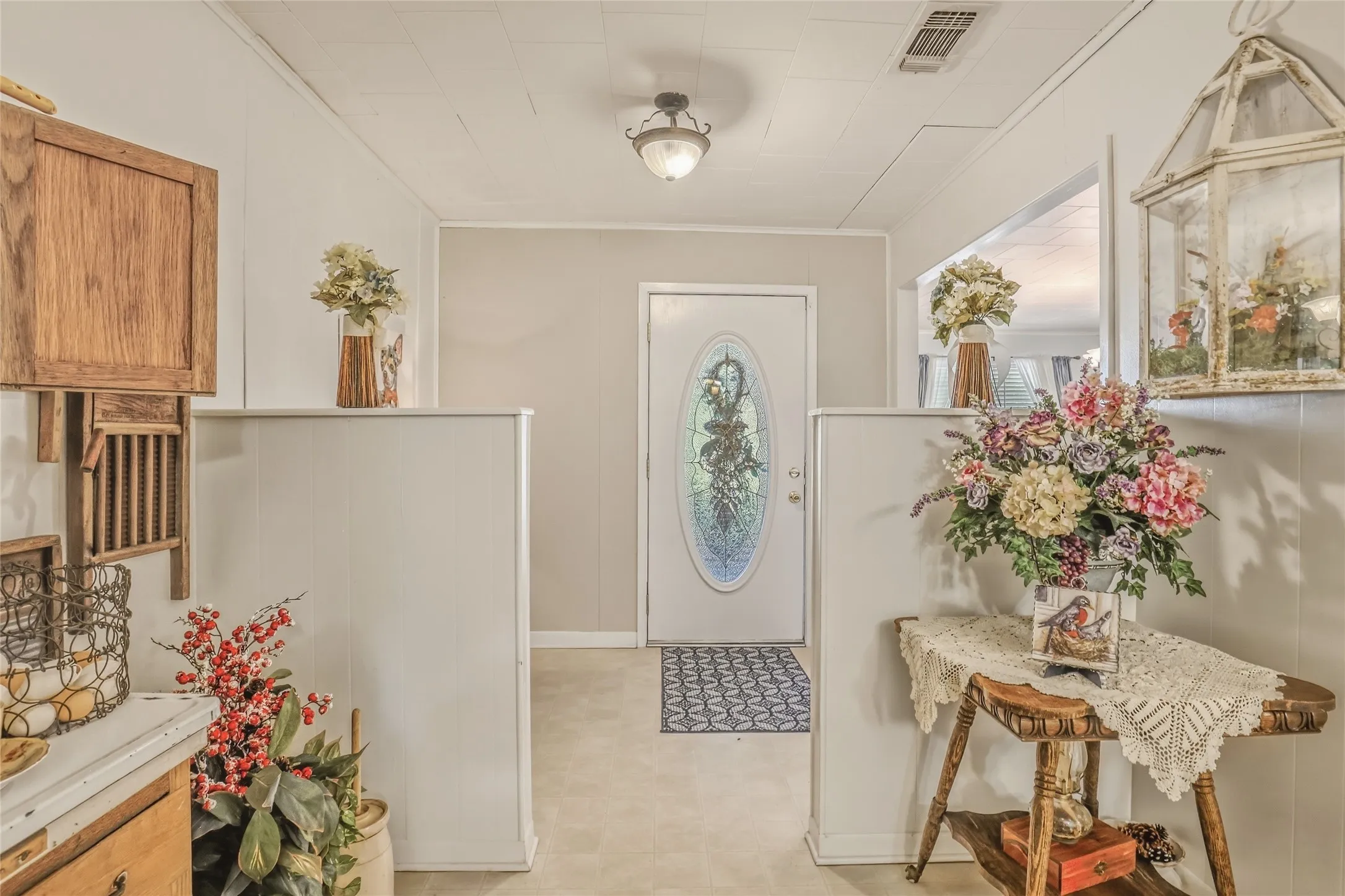 Entryway featuring a white door with an oval stained-glass insert, light-colored flooring, and light wall paneling