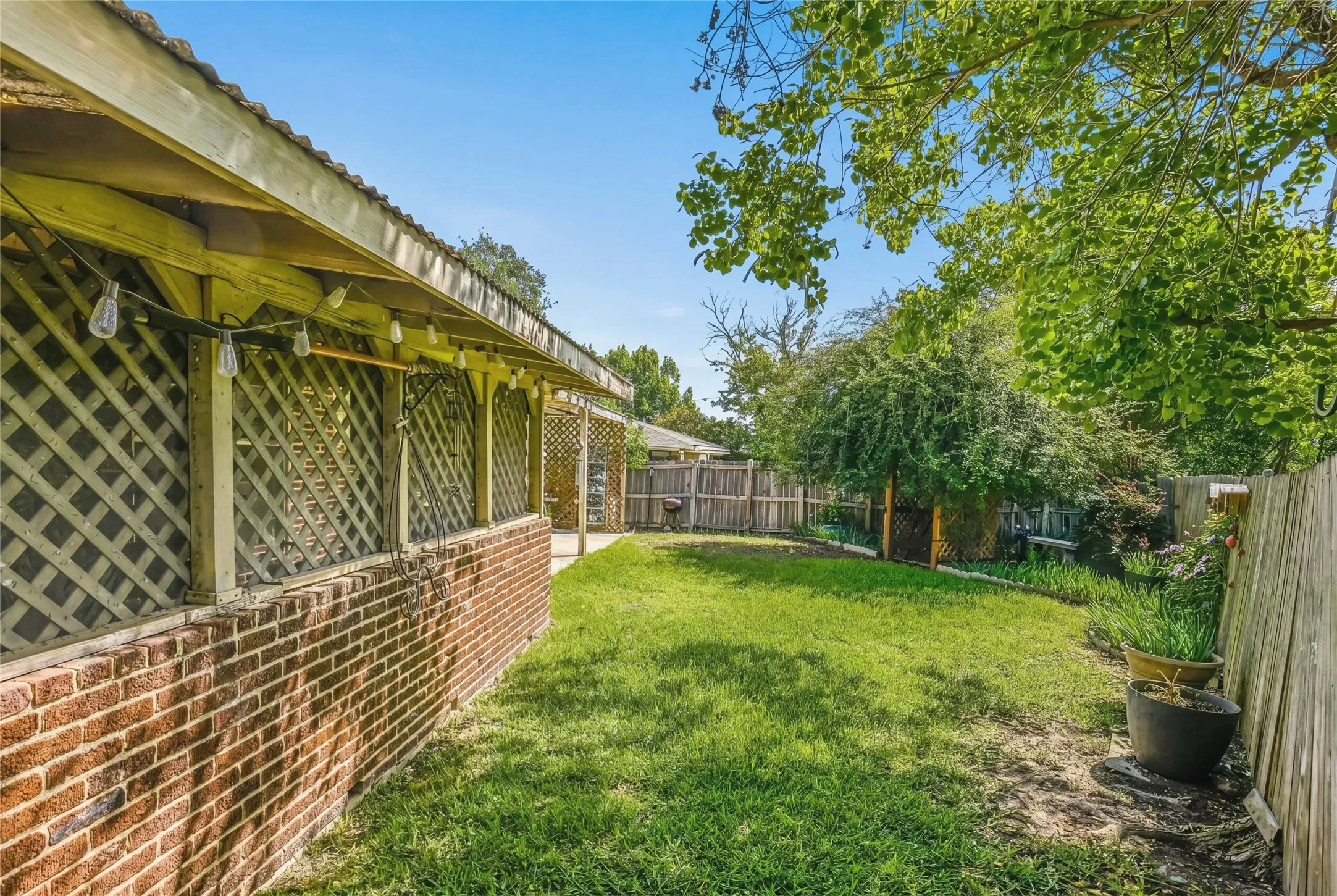 Expansive backyard featuring a manicured lawn, established perimeter fencing, and mature trees