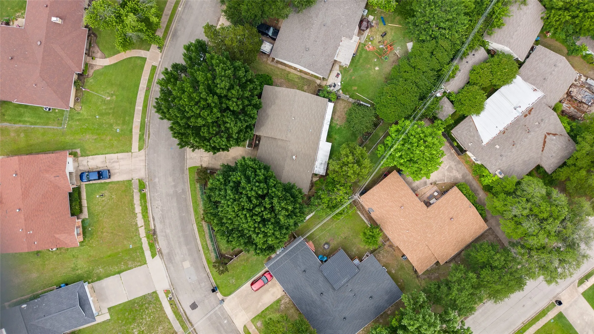 Residential neighborhood featuring established homes with various roof materials and mature tree coverage