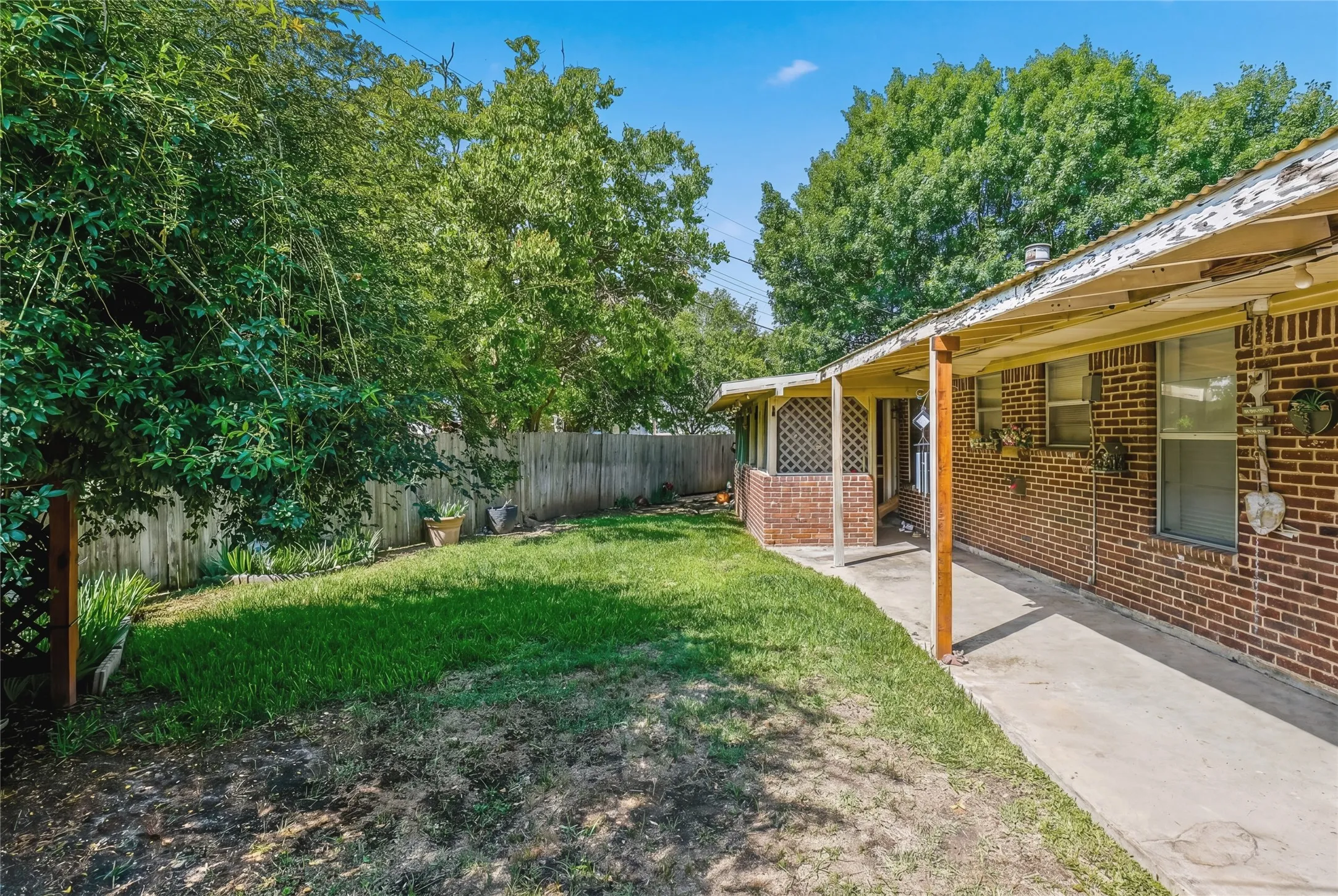 Expansive backyard featuring a manicured lawn, established trees, and a privacy fence