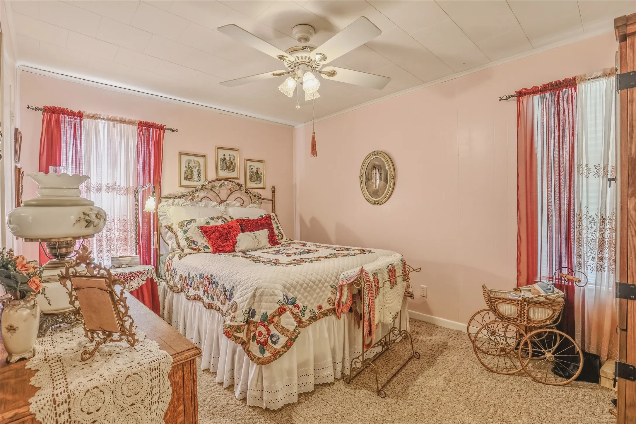 Carpeted room featuring a ceiling fan with integrated lighting, a window with curtain rod and sheer and opaque drapes, and light pink wall paneling