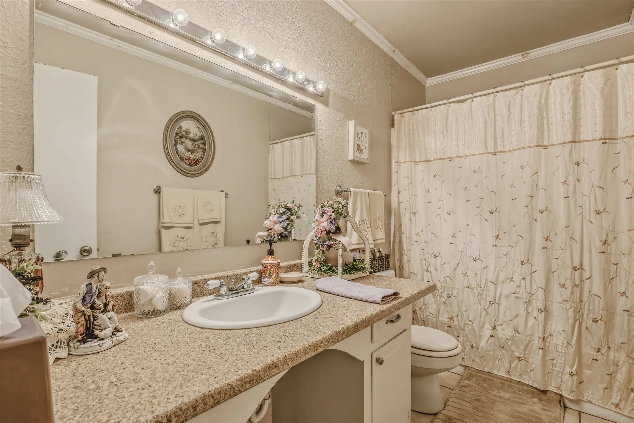 Bathroom vanity with a speckled countertop, integrated sink, and white cabinetry