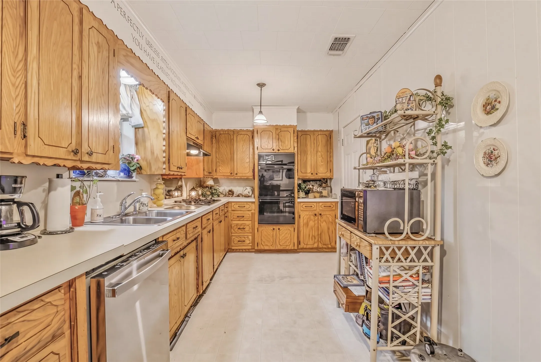 U-shaped kitchen featuring wood cabinetry, built-in double ovens, white countertops, and a double basin stainless steel sink