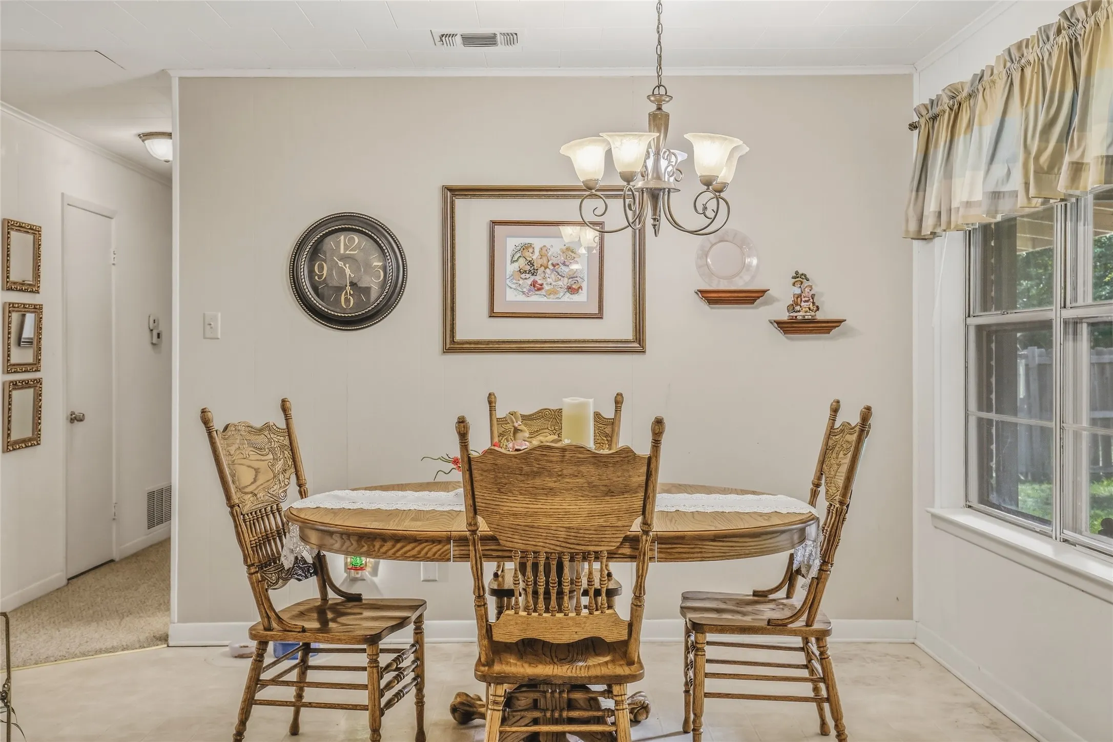 Dining area featuring light-toned walls, a multi-pane window, and a ceiling-mounted chandelier