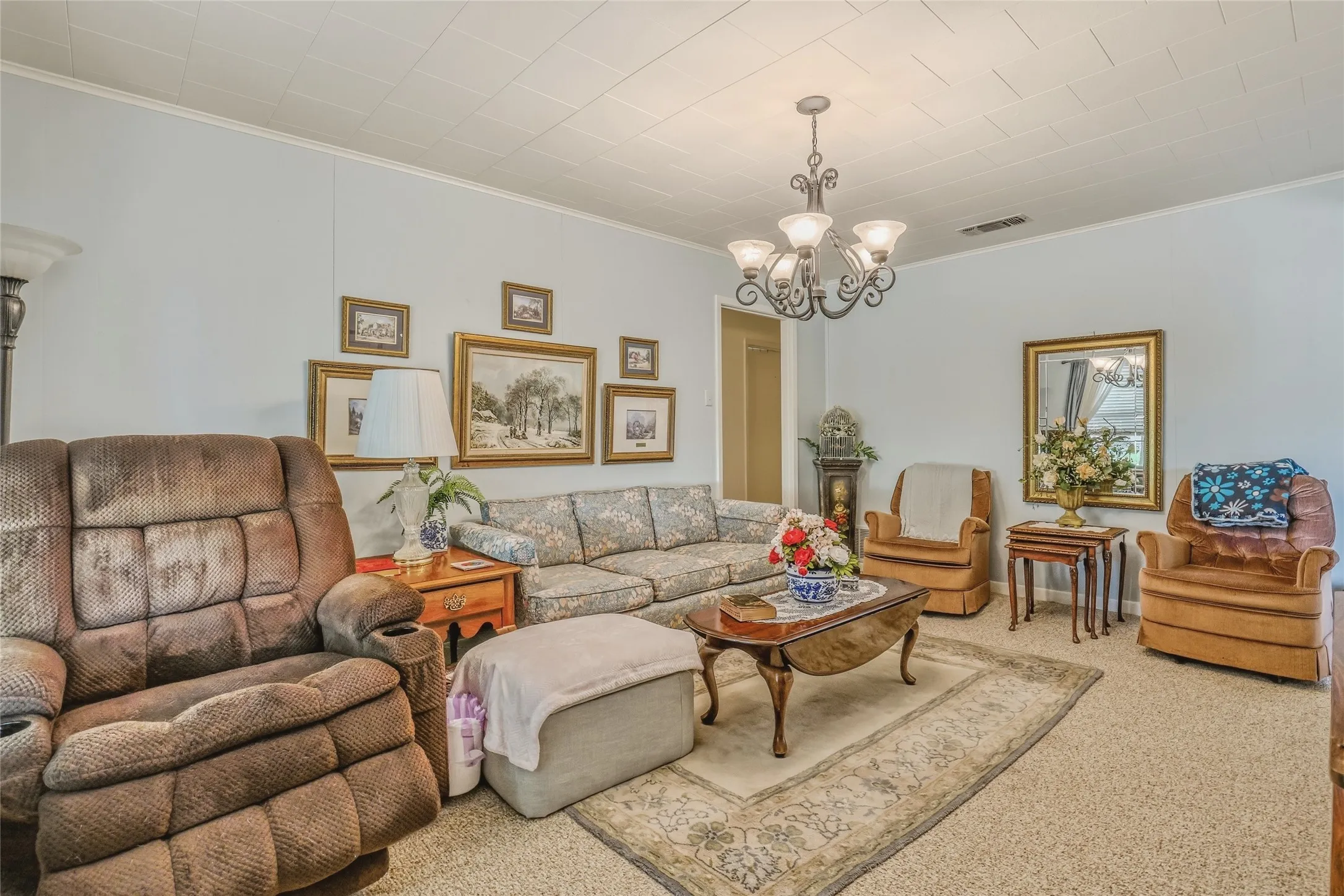 Inviting living space featuring light blue walls, textured ceiling, a decorative chandelier, and plush carpeting