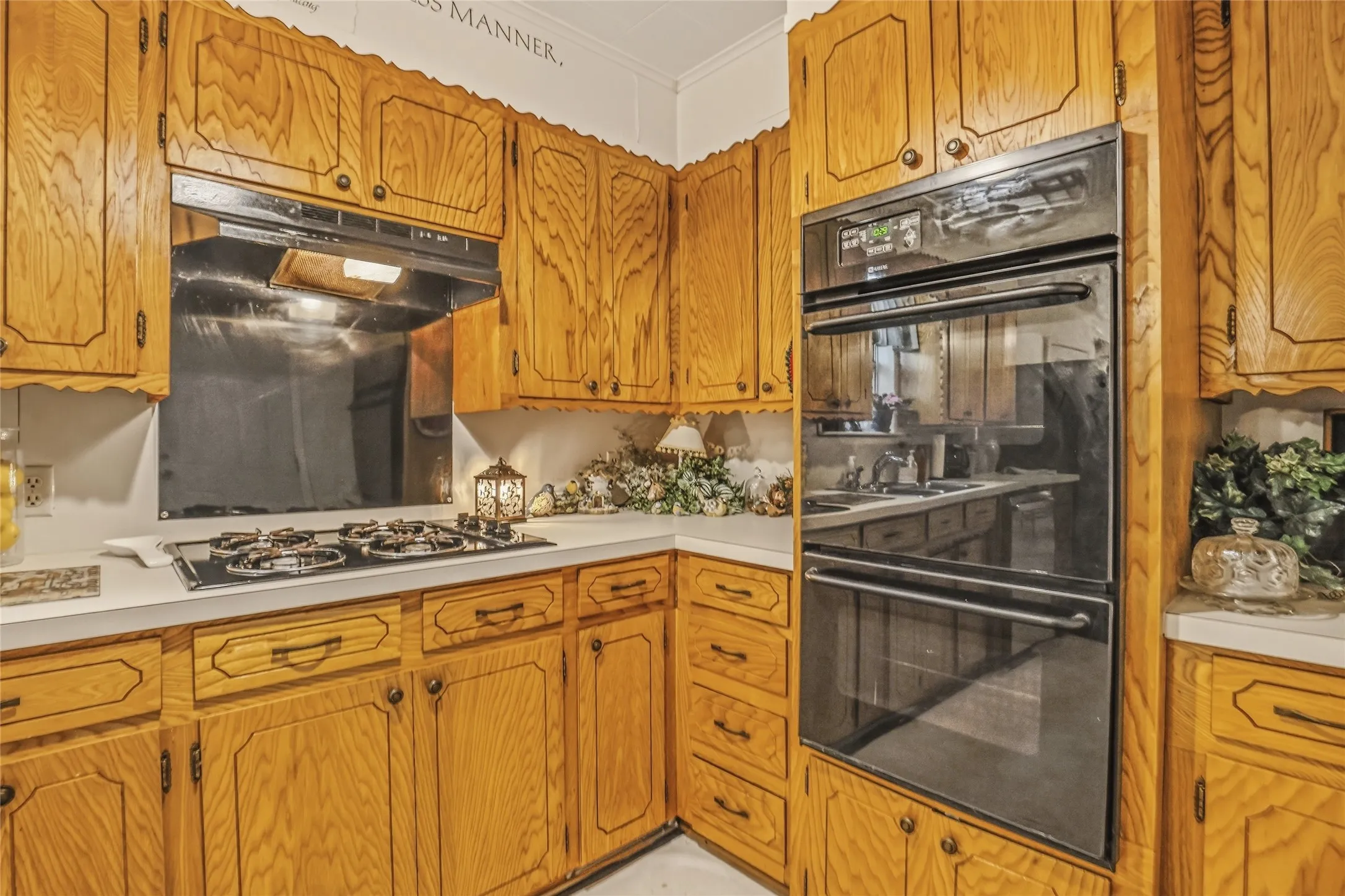 Kitchen featuring wood cabinetry, white countertops, built-in double ovens, and a gas cooktop with an integrated range hood