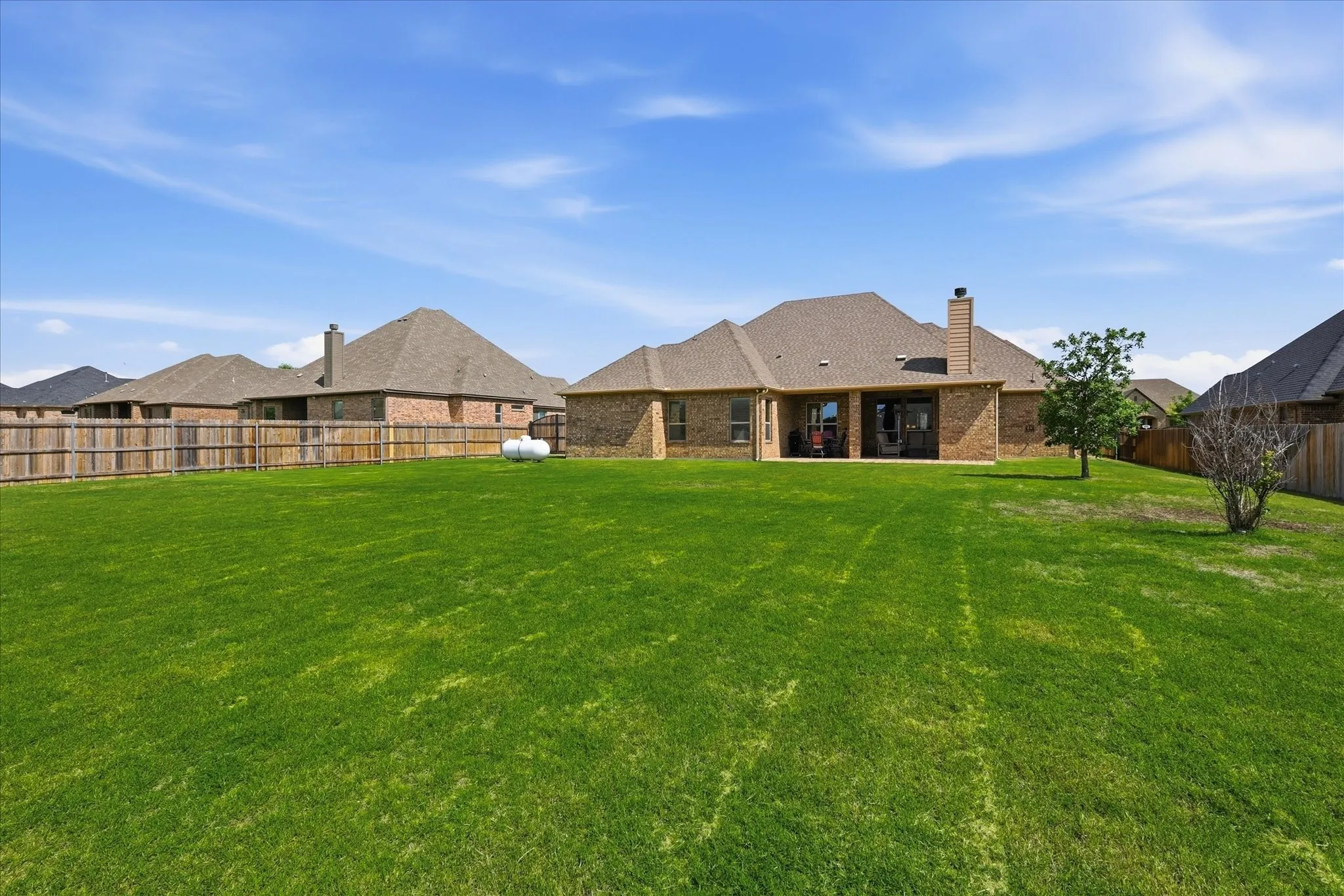 Expansive green lawn with a full privacy fence encompassing the property