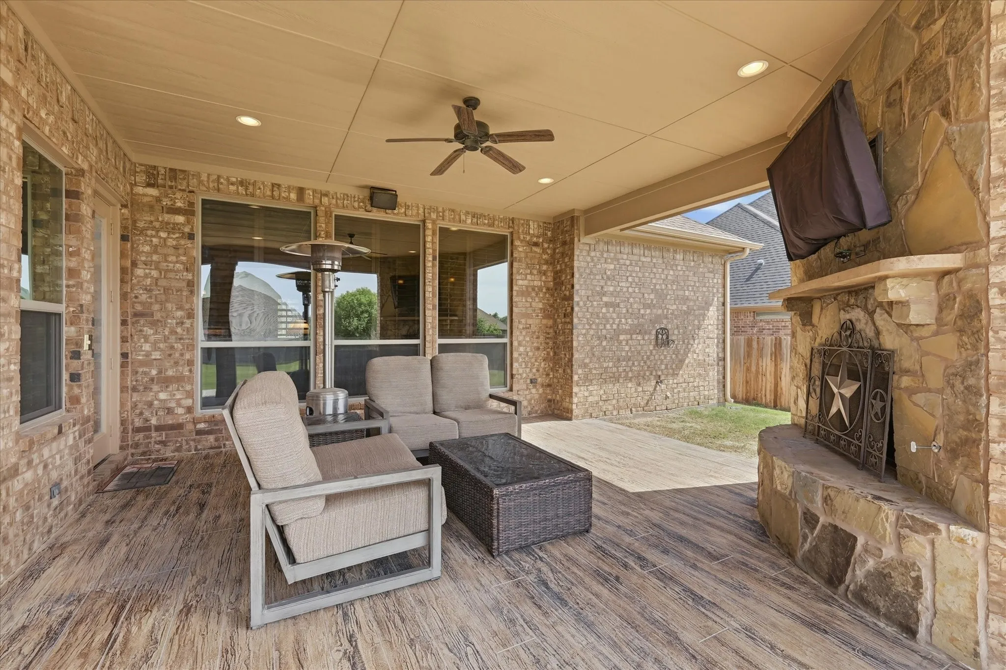 Covered outdoor patio featuring a stone-clad fireplace with a mantel, recessed lighting, a ceiling fan, and wood-finish flooring