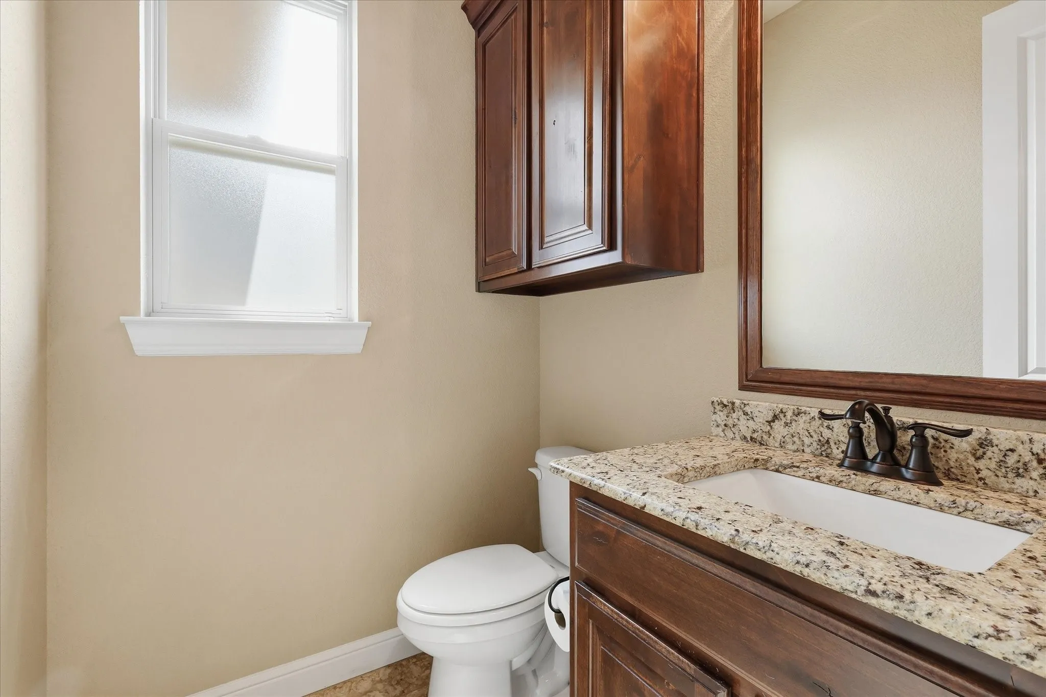 Vanity featuring a stone countertop with an undermount sink, dark wood cabinetry, and an oil-rubbed bronze faucet