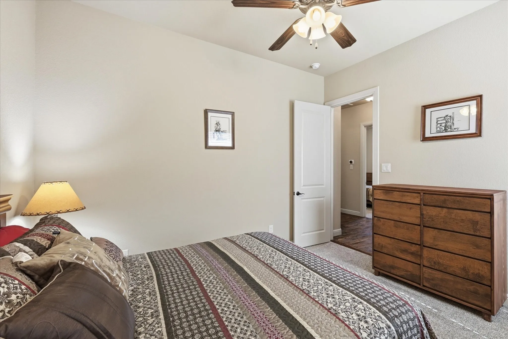 Carpeted bedroom with a ceiling fan light fixture, light neutral wall paint, and a white interior door