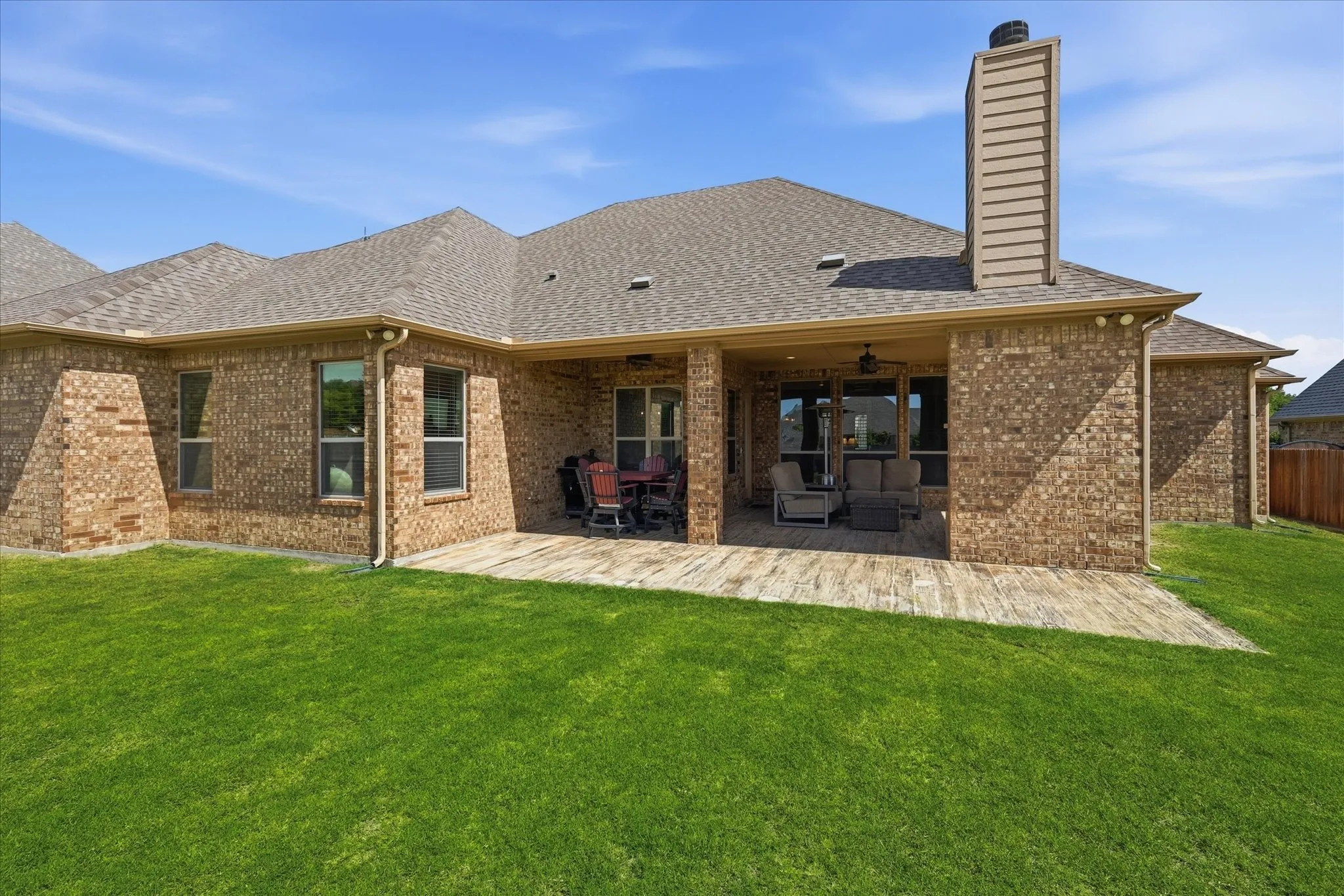 Expansive backyard featuring a covered patio with patterned concrete flooring