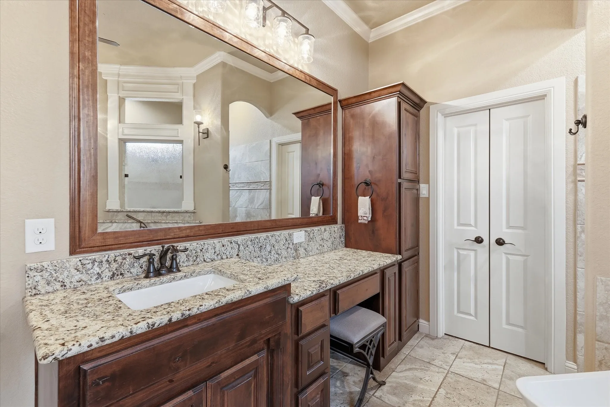 Bathroom vanity featuring a granite countertop, undermount sink, and dark wood cabinetry