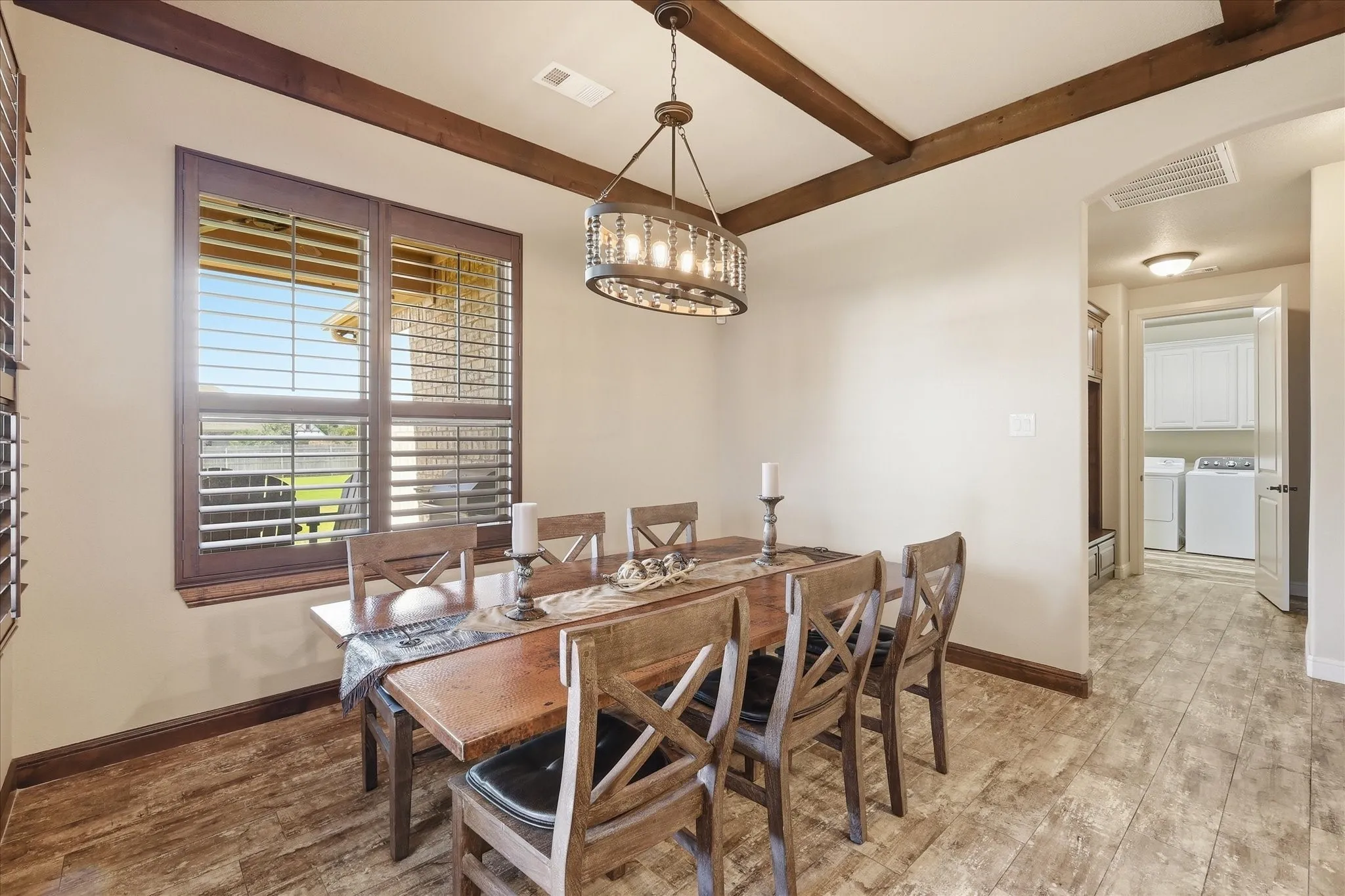 Dining area with wood-finish flooring, exposed ceiling beams, and a wagon wheel chandelier