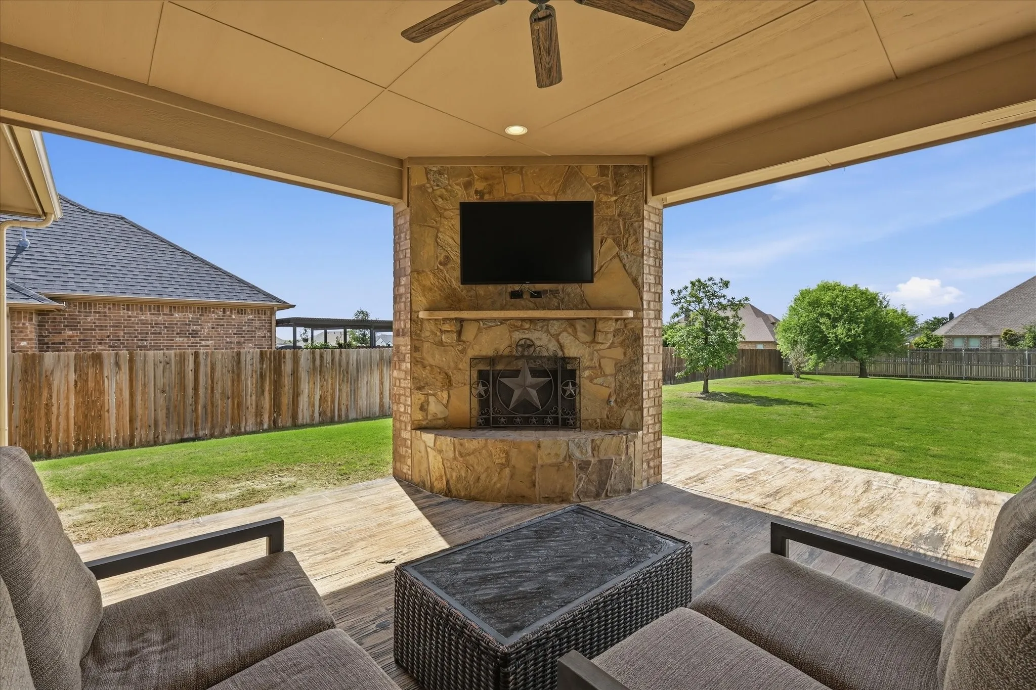 Covered patio featuring a stone fireplace with hearth, built-in media niche, and a ceiling fan