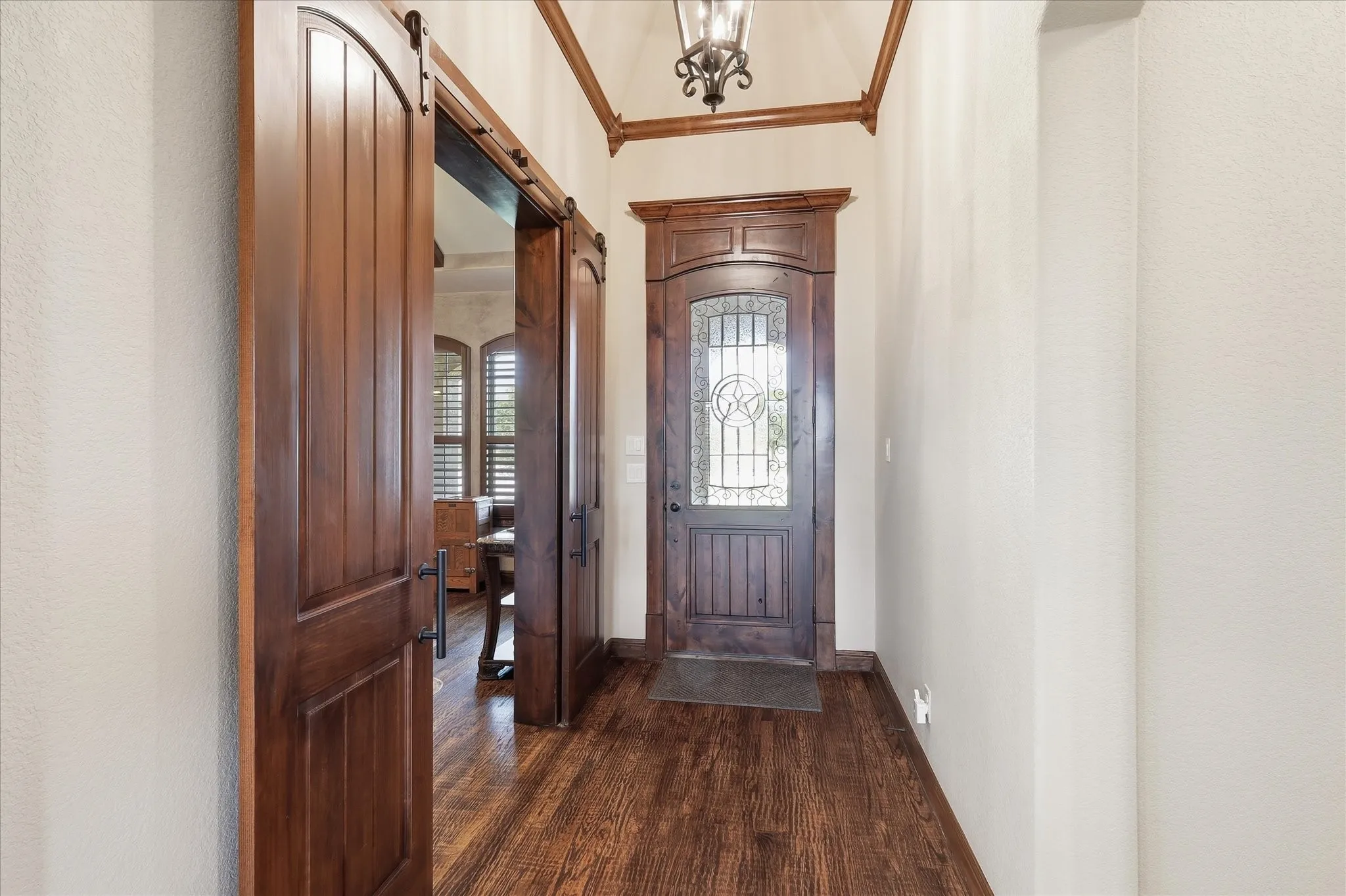 Entryway featuring rich wood-finish flooring, a decorative front door with leaded glass, and a vaulted ceiling with exposed wood beams