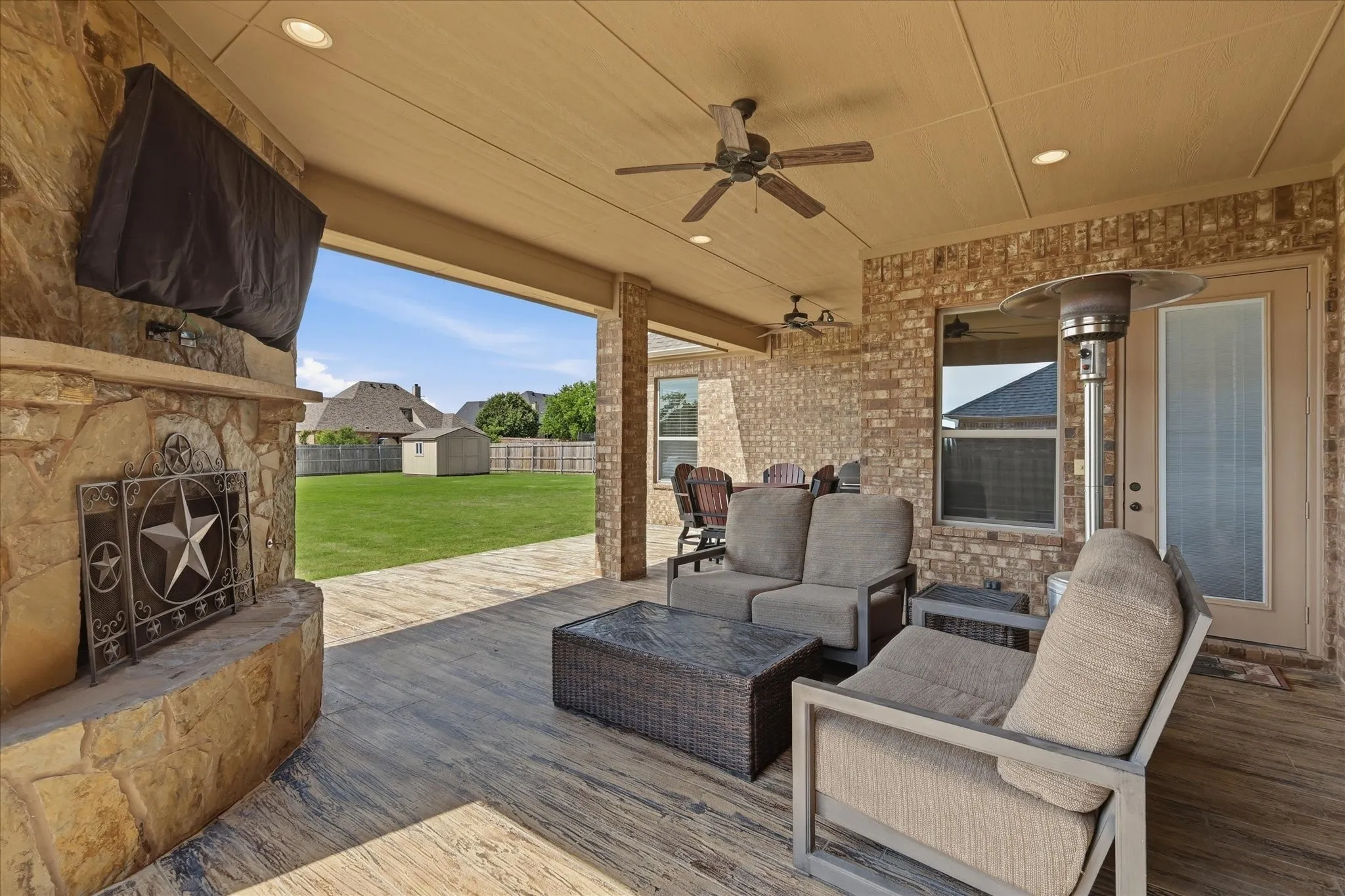 Expansive covered patio featuring a stone fireplace, recessed lighting, and multiple ceiling fans